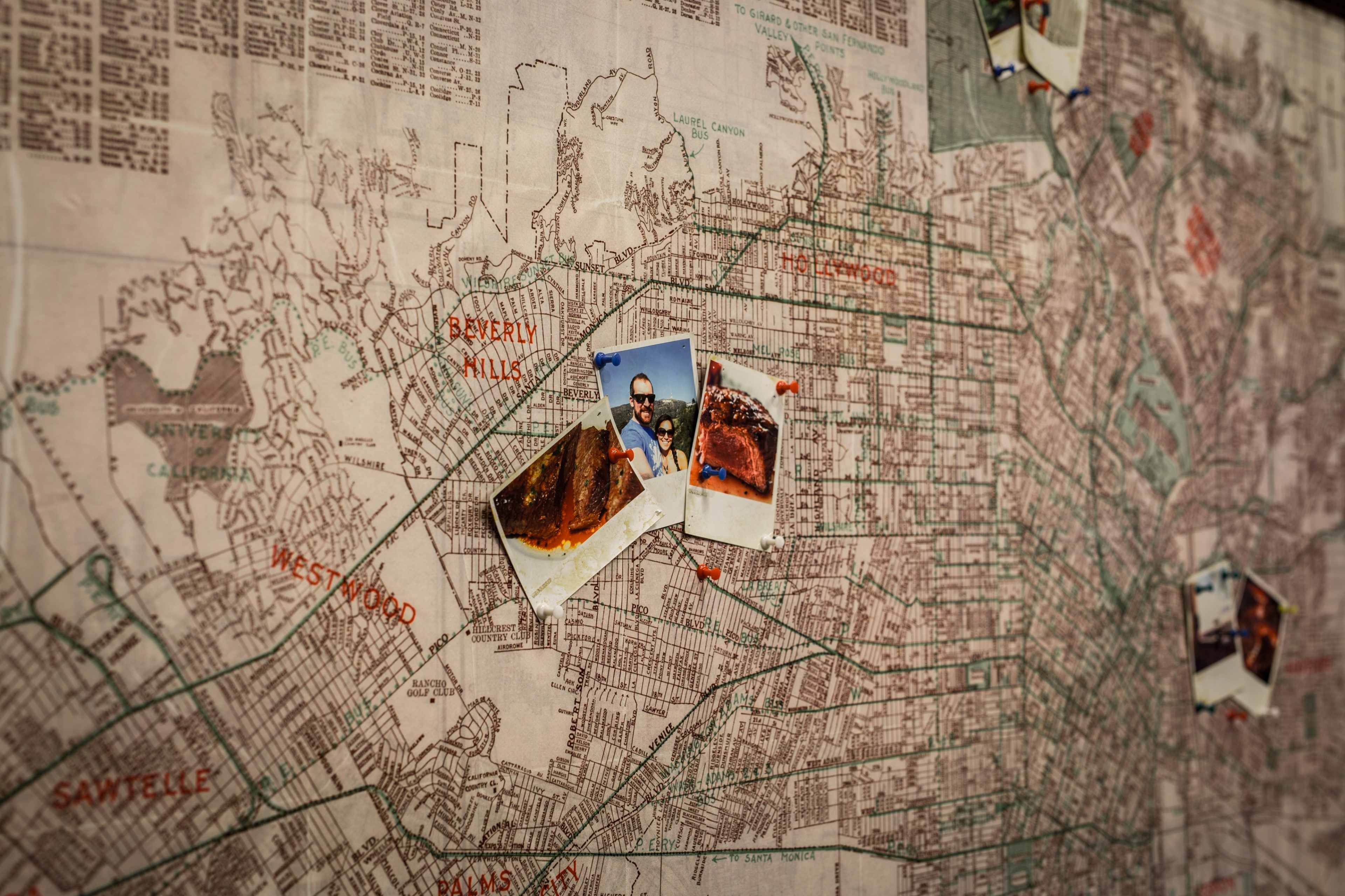 A map of Los Angeles is decorated with several photographs pinned to it, highlighting specific locations.