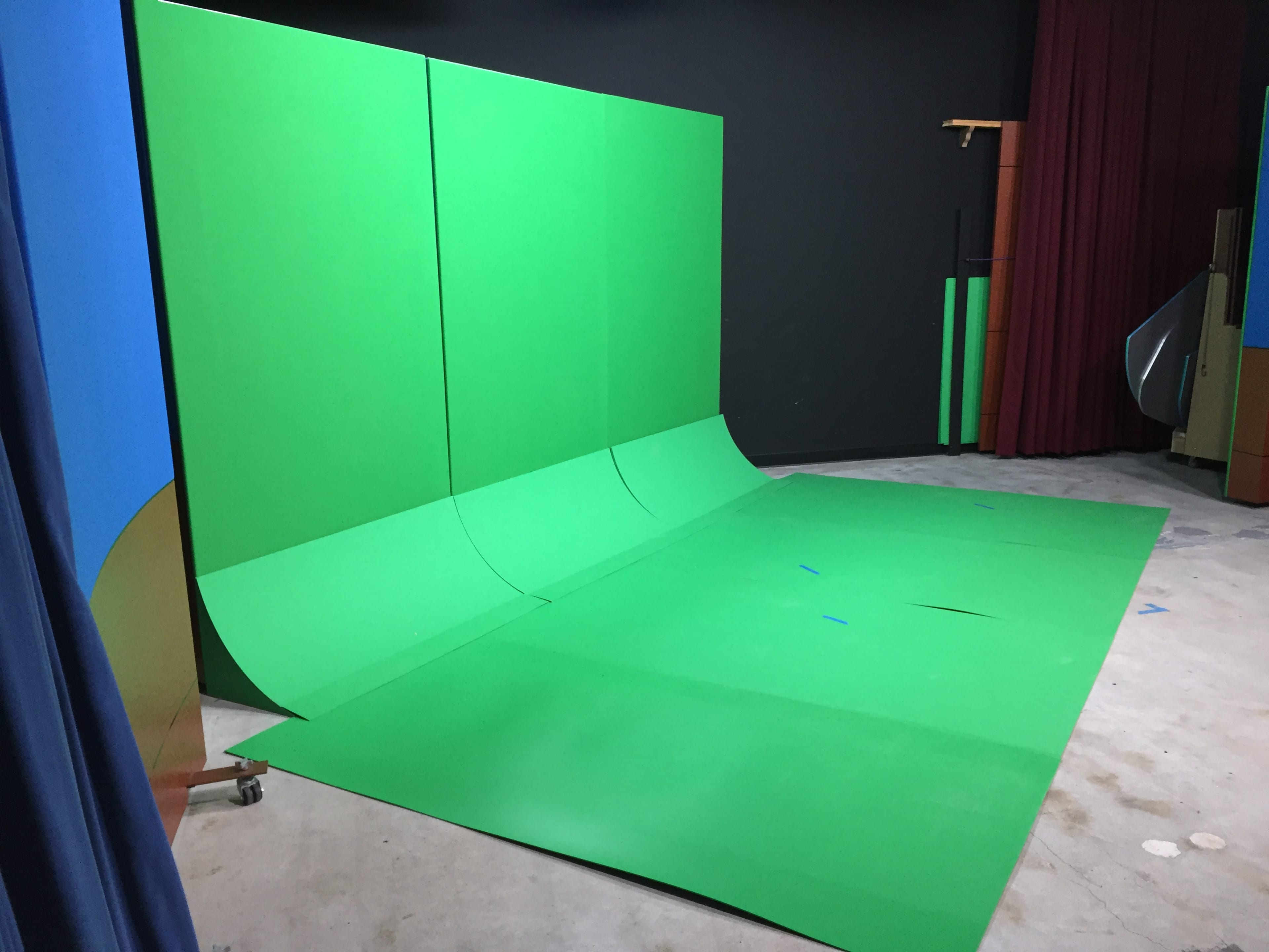 A studio setup featuring a large green screen backdrop and a matching green floor.