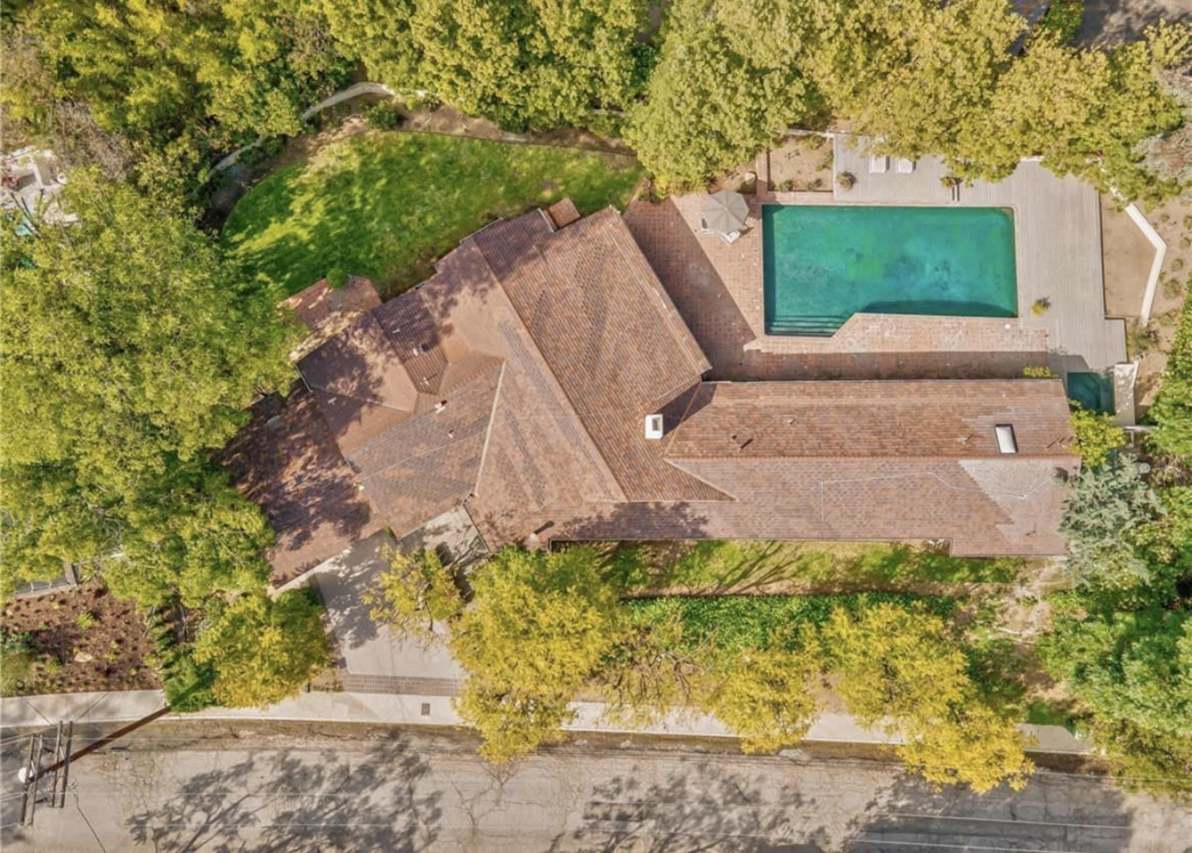 The image shows an aerial view of a large house with a swimming pool and landscaped grounds.
