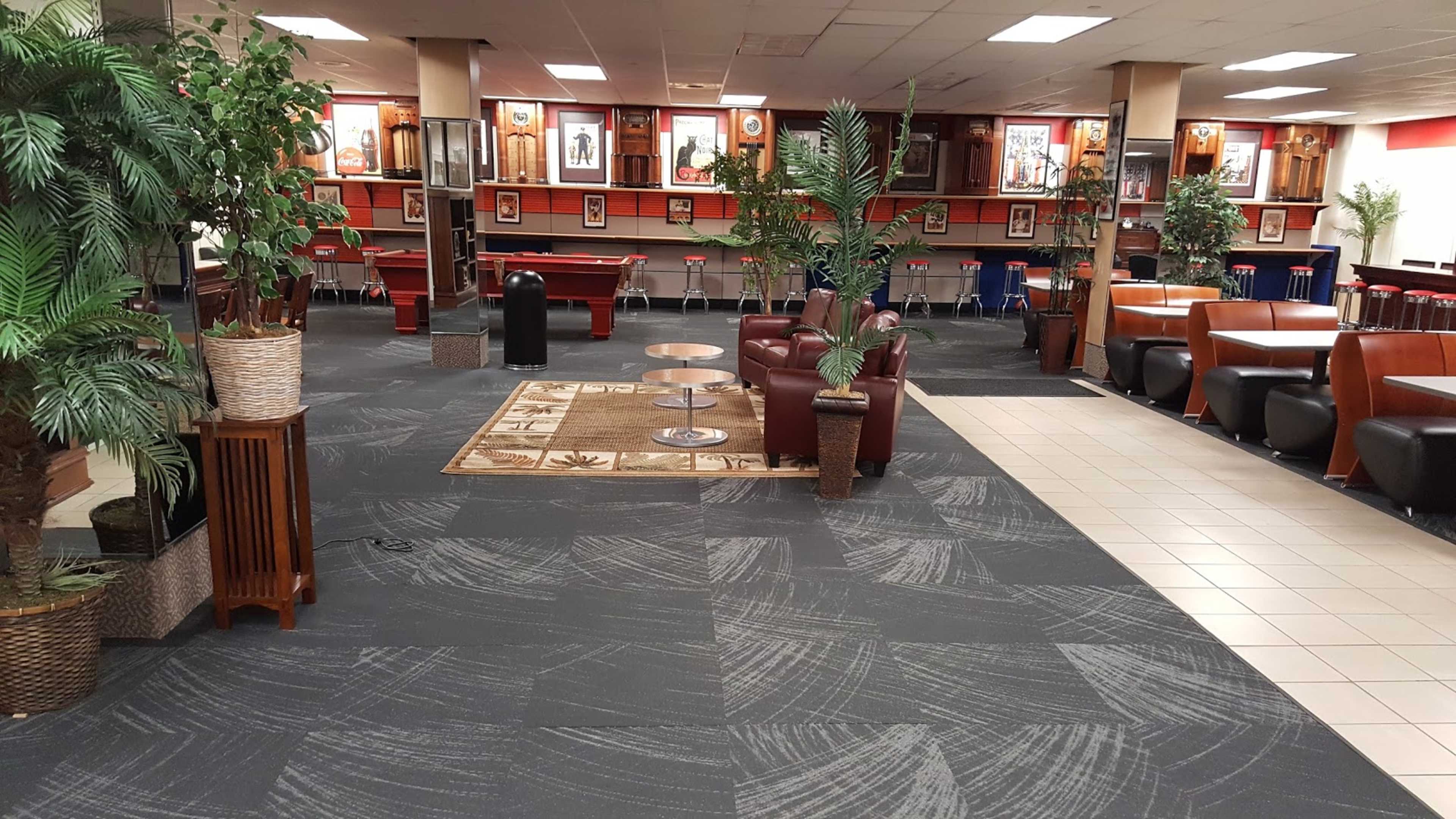 A spacious recreational area featuring seating arrangements, plants, and decorative wall art.