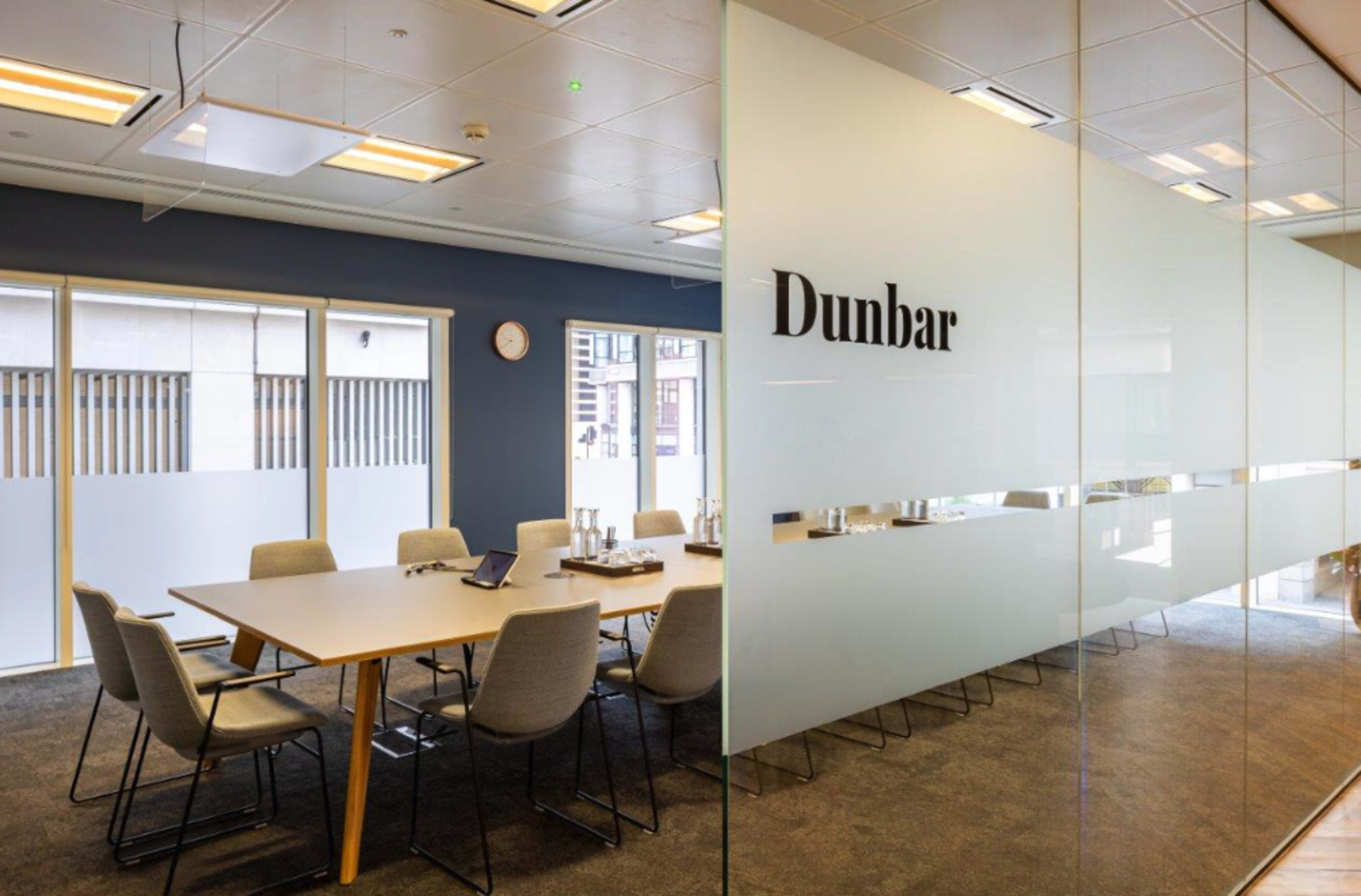 A modern conference room featuring a large table surrounded by chairs and a glass wall labeled "Dunbar."