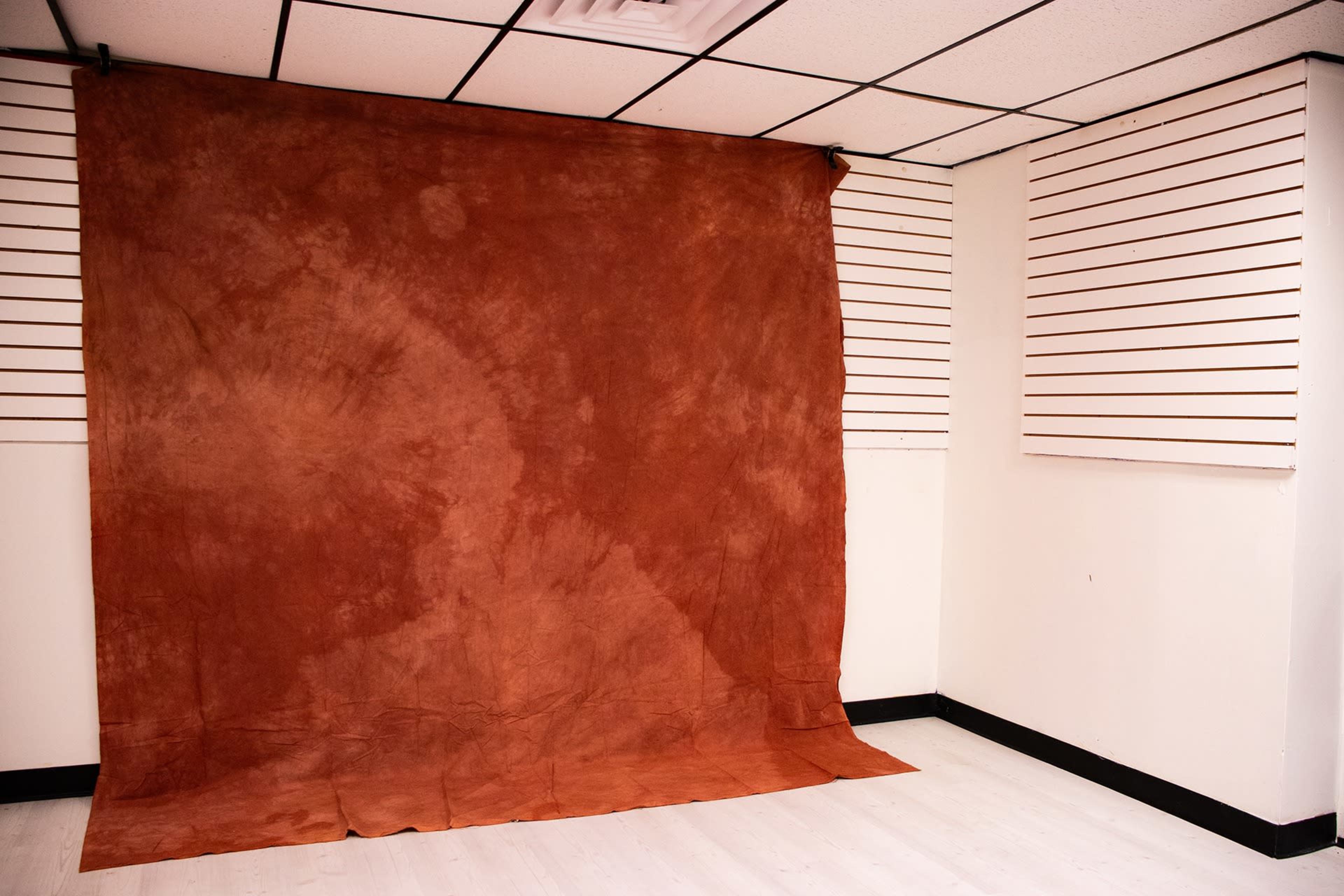 A room with a large brown backdrop draped against the wall, surrounded by white paneling and a light-colored floor.