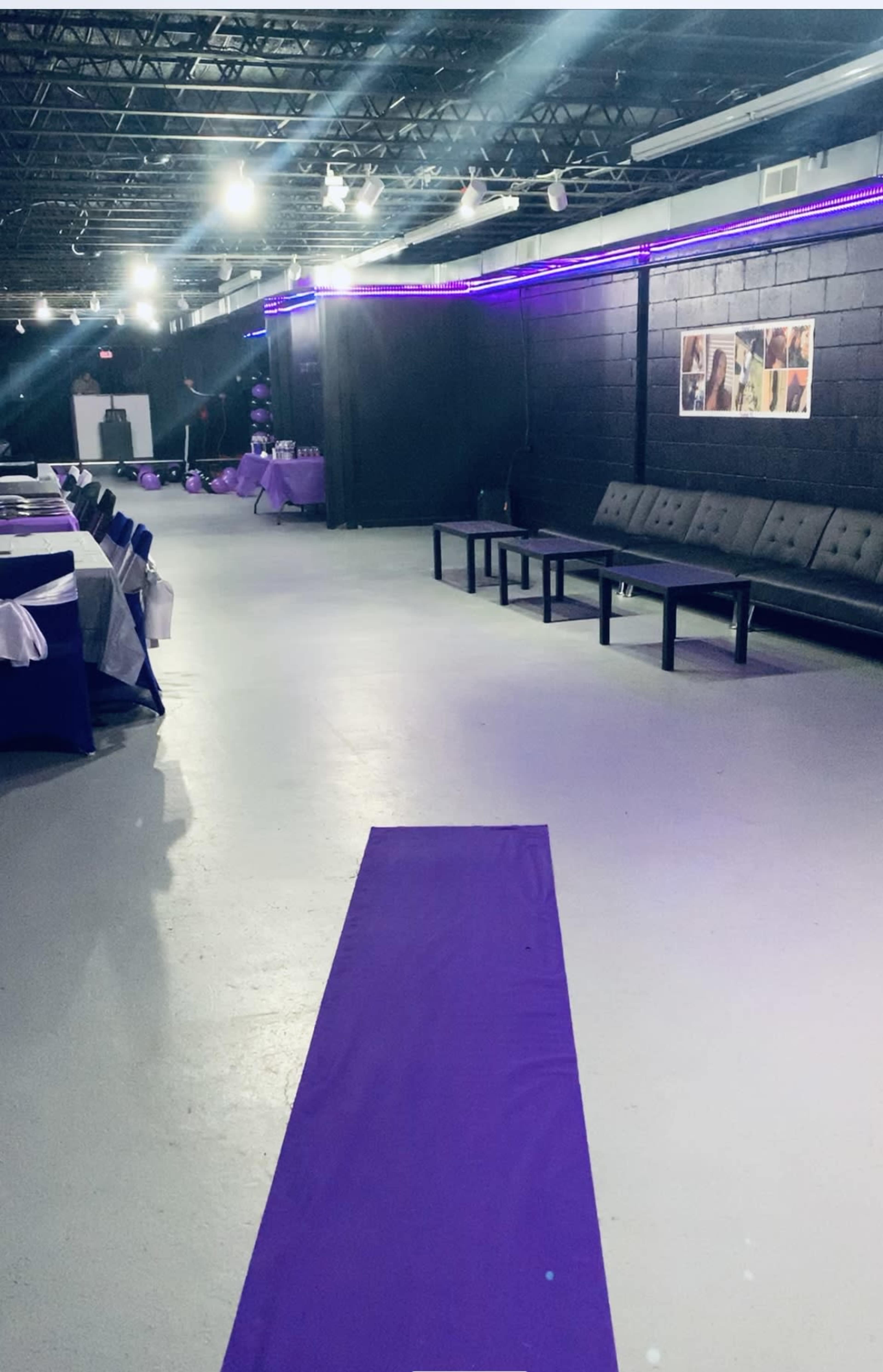 A long purple runner extends down the center of an event space lined with tables and seating.