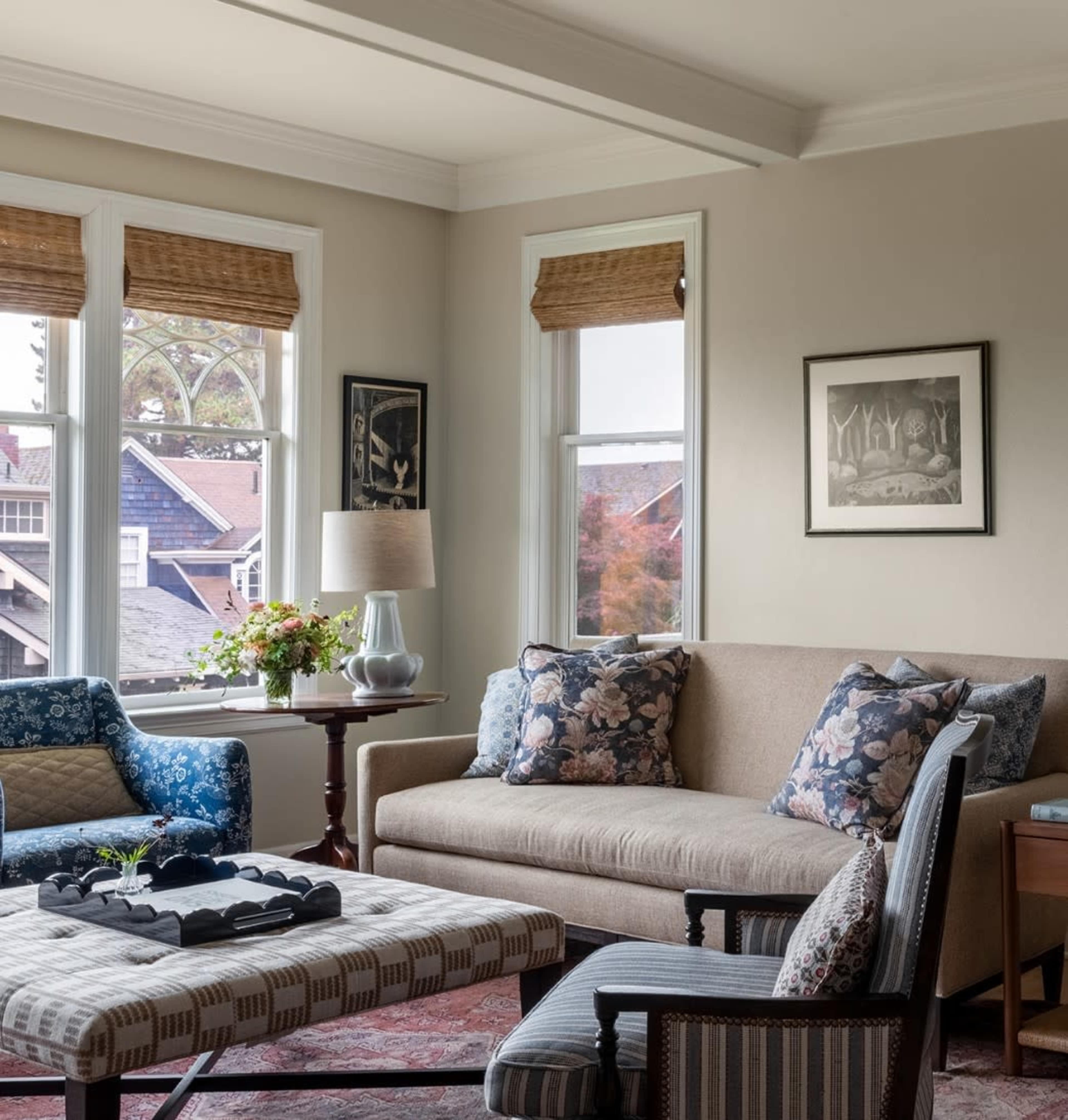 The living room features a sofa and chairs arranged around a coffee table, with large windows allowing natural light to illuminate the space.