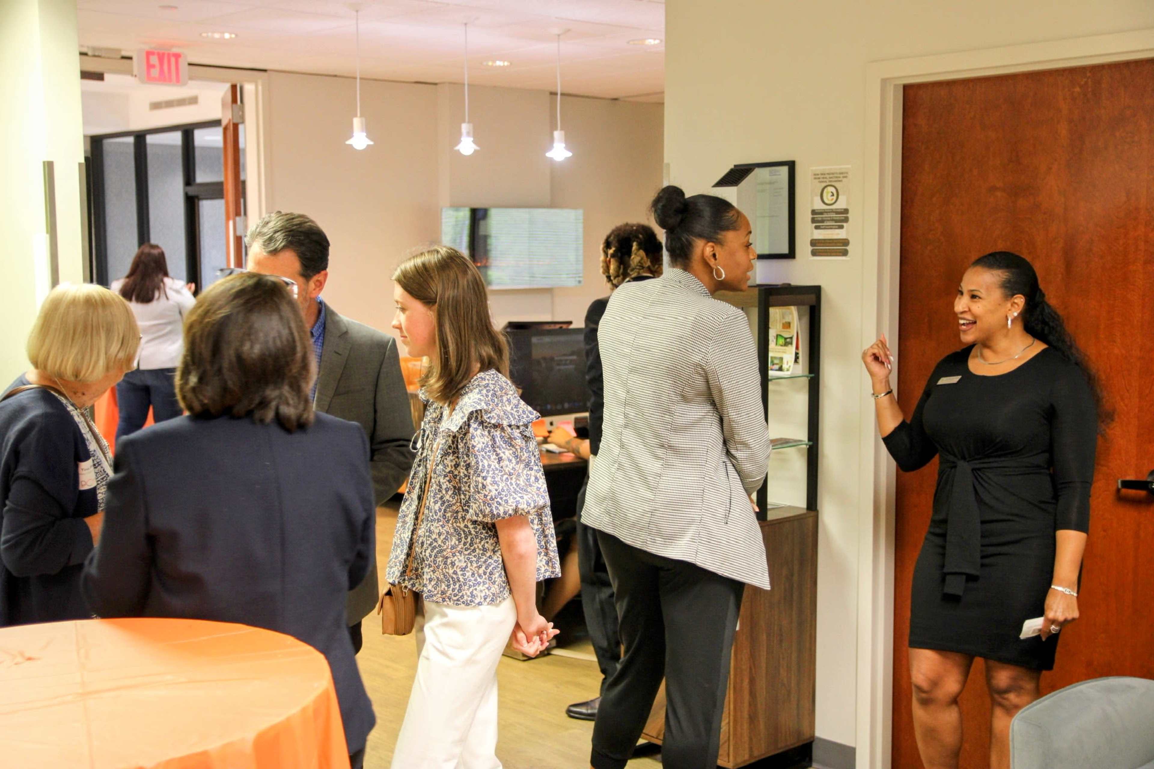 A group of people engage in conversation at a networking event in a modern office setting.
