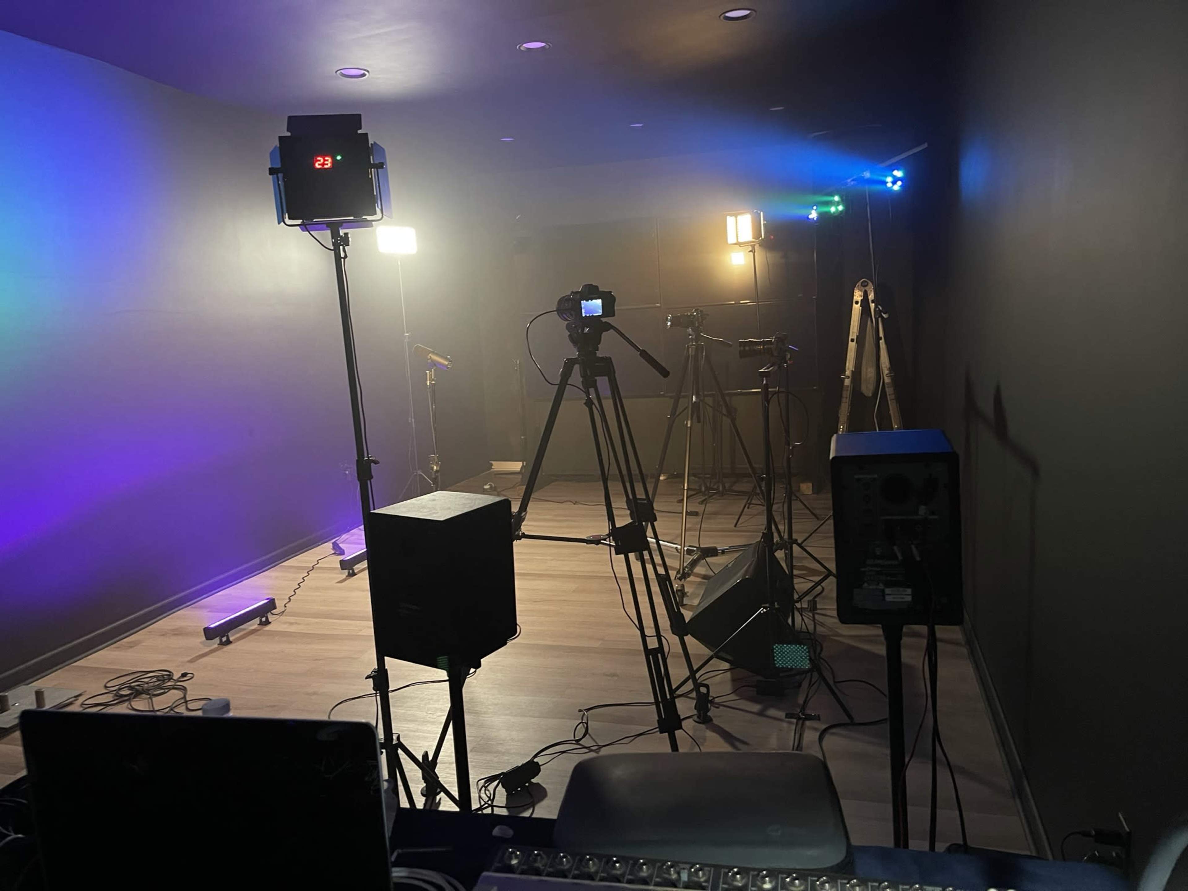 A studio setup with multiple lights, cameras on tripods, and various equipment arranged on the floor.