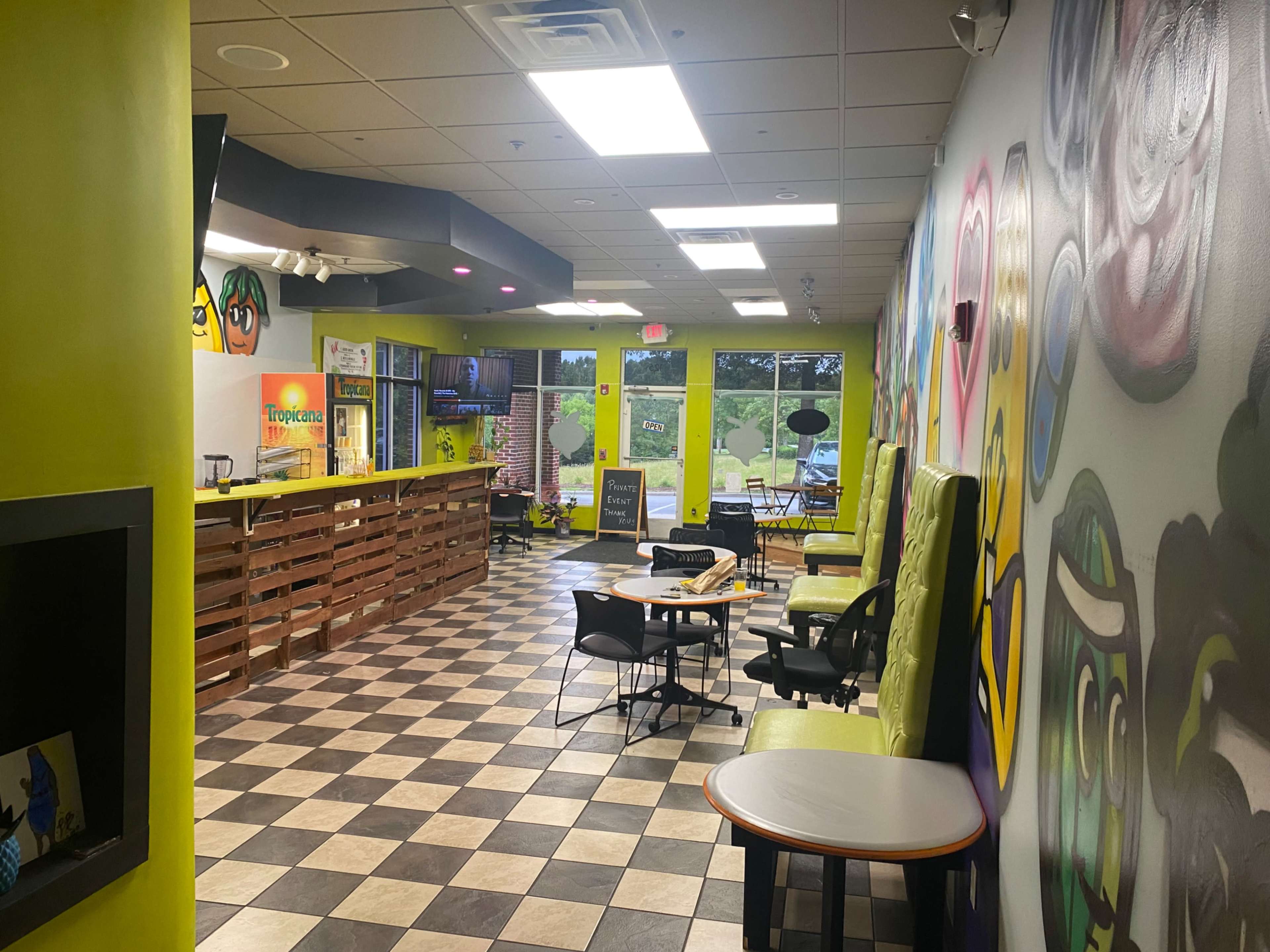 A colorful café interior with a checkered floor, vibrant walls, and seating areas.