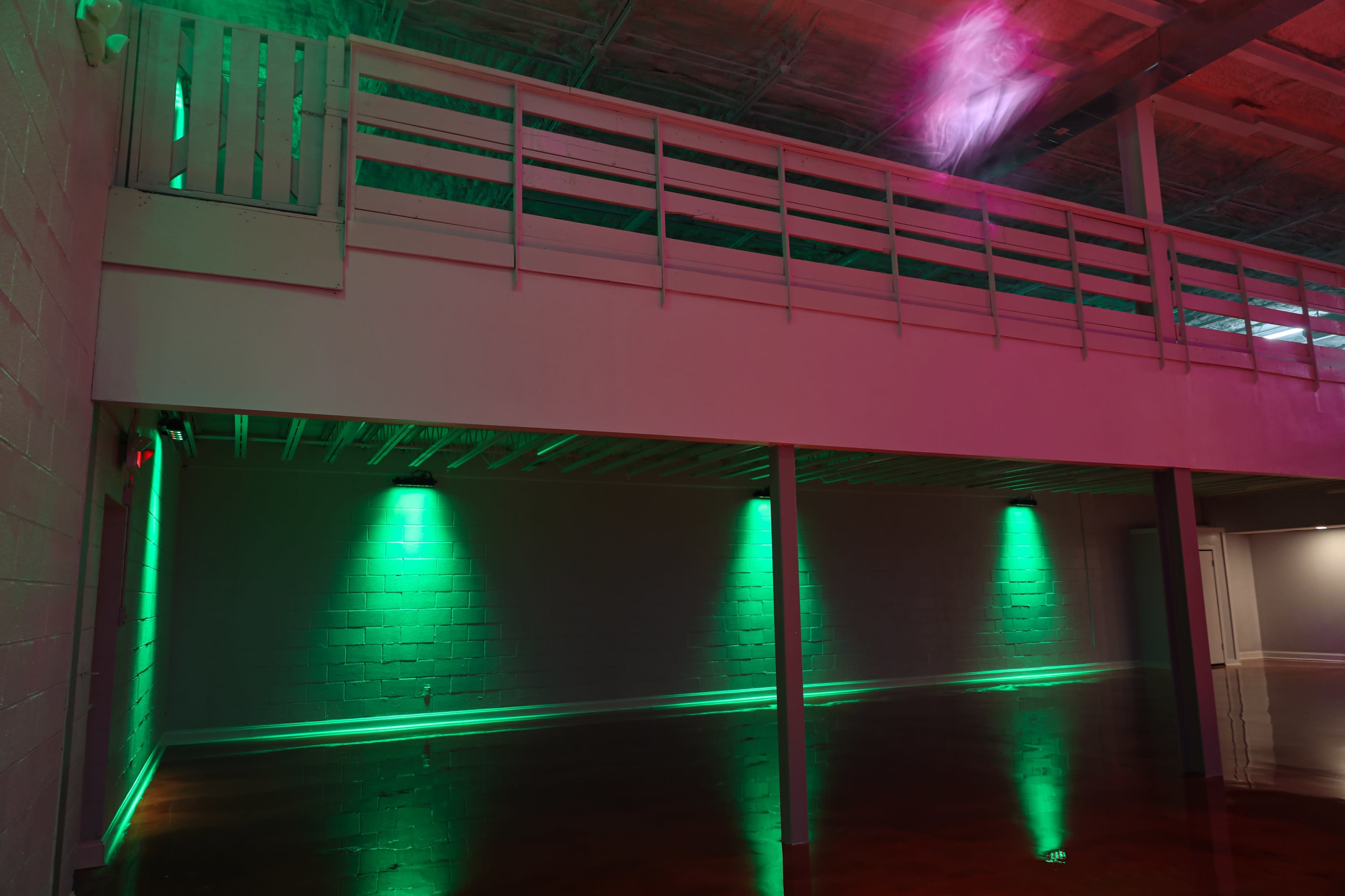 A spacious interior features a mezzanine level and green LED lights illuminating the floor and walls.