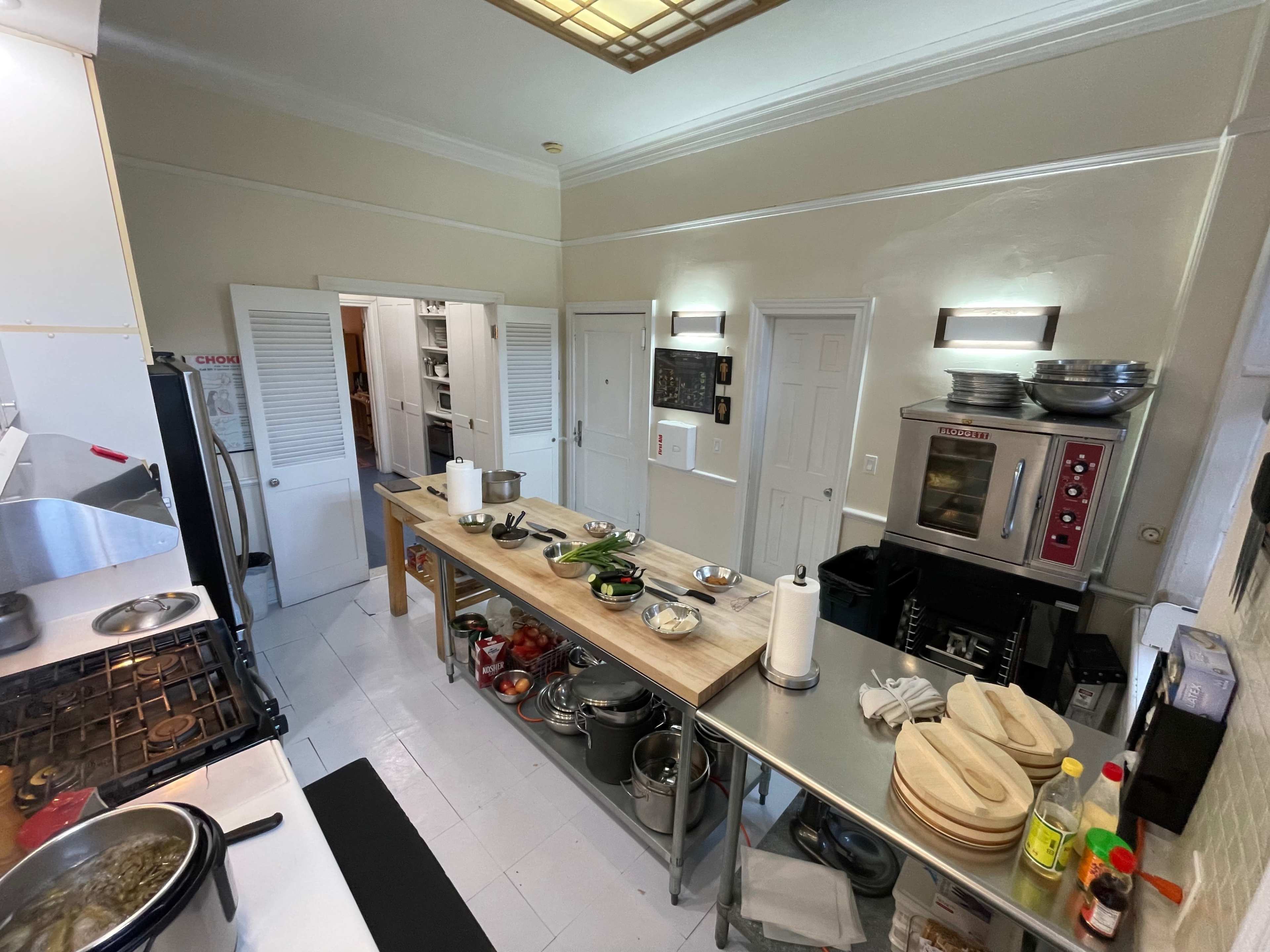 A spacious kitchen with stainless steel tables, cabinets, and various culinary tools neatly arranged throughout.