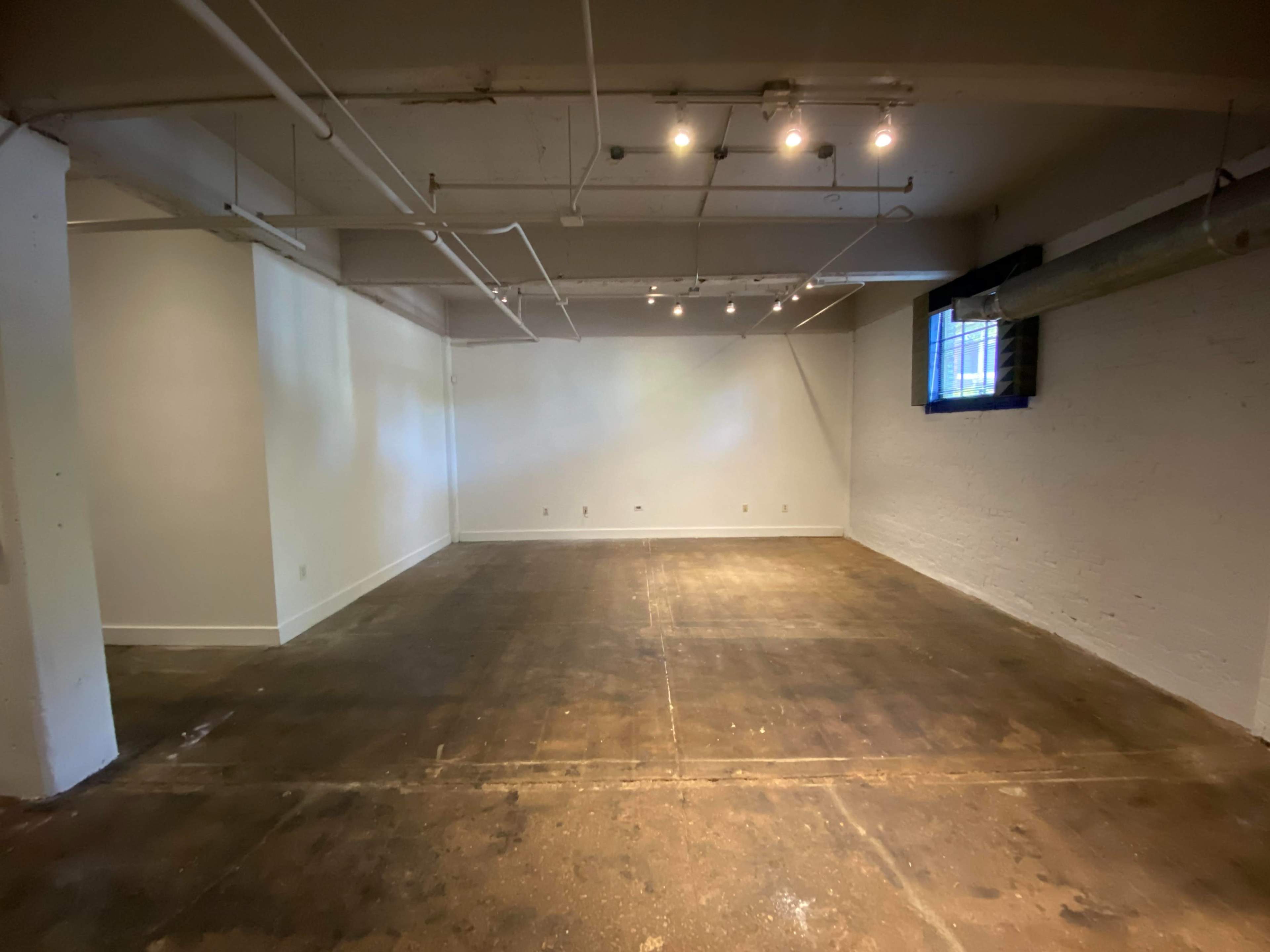 An empty, well-lit room with concrete flooring and white walls.