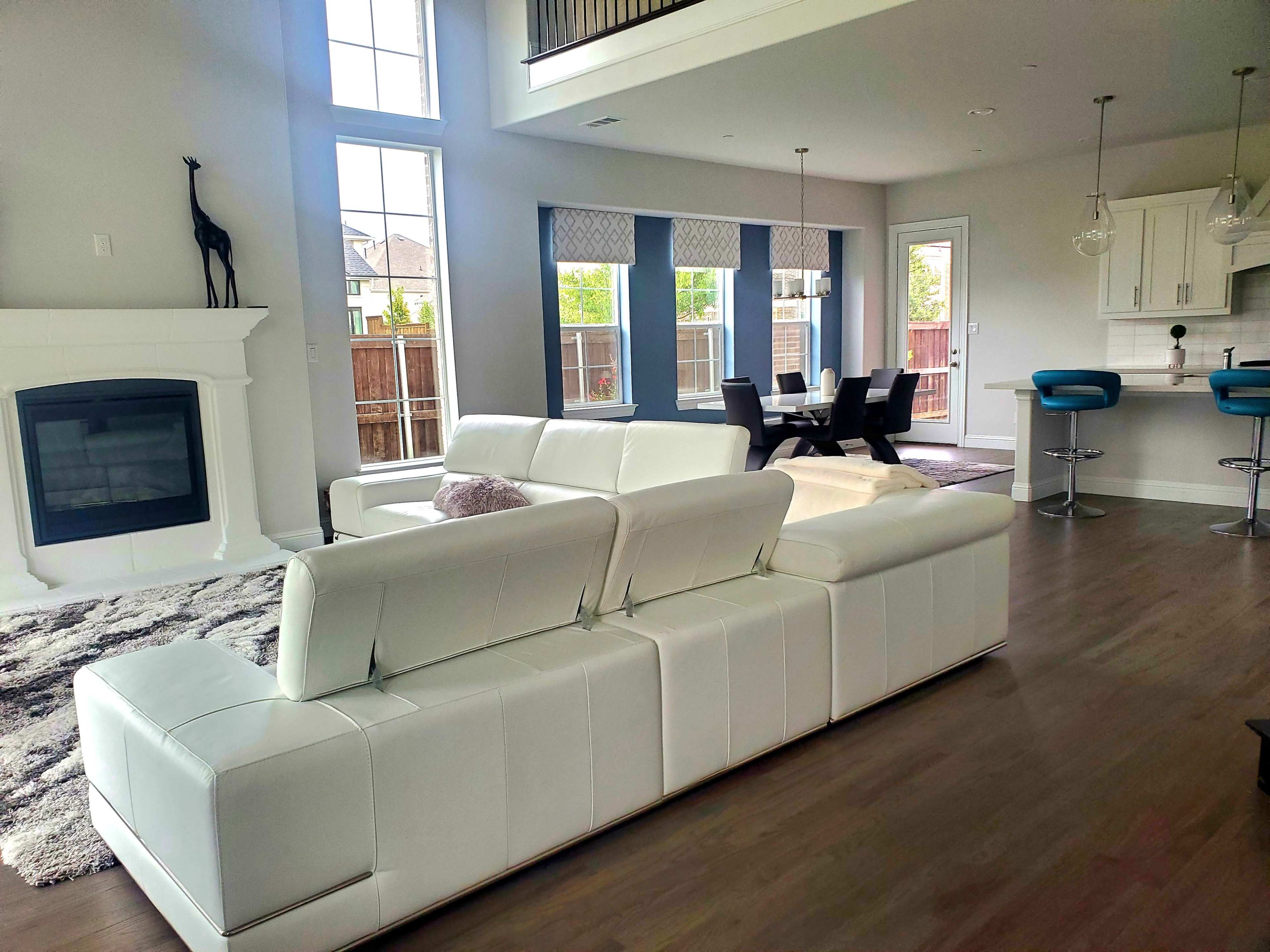 A modern living room with a white sectional sofa, a fireplace, and large windows letting in natural light.