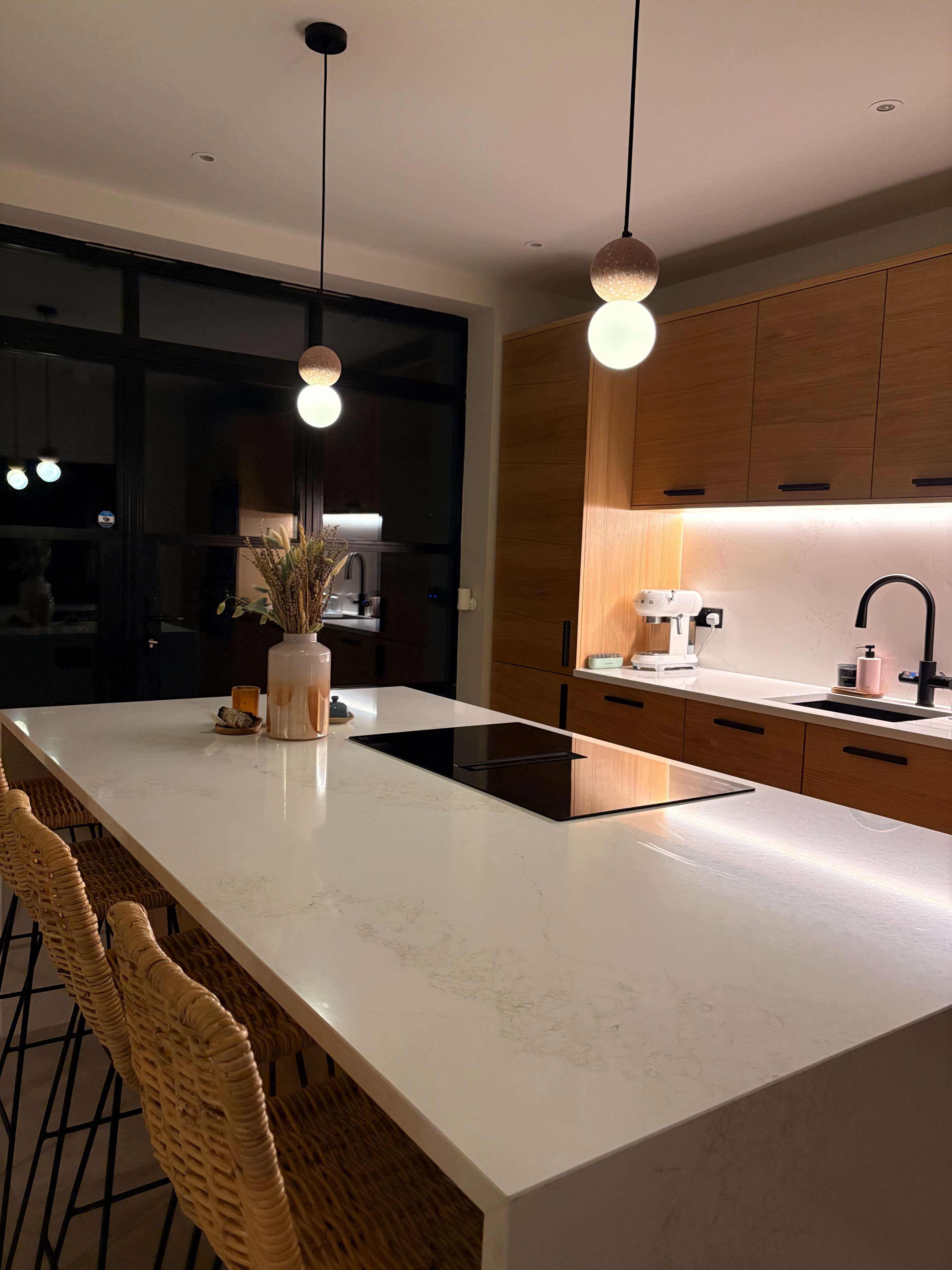 The kitchen features a large island with barstools, modern pendant lights, and wooden cabinetry.