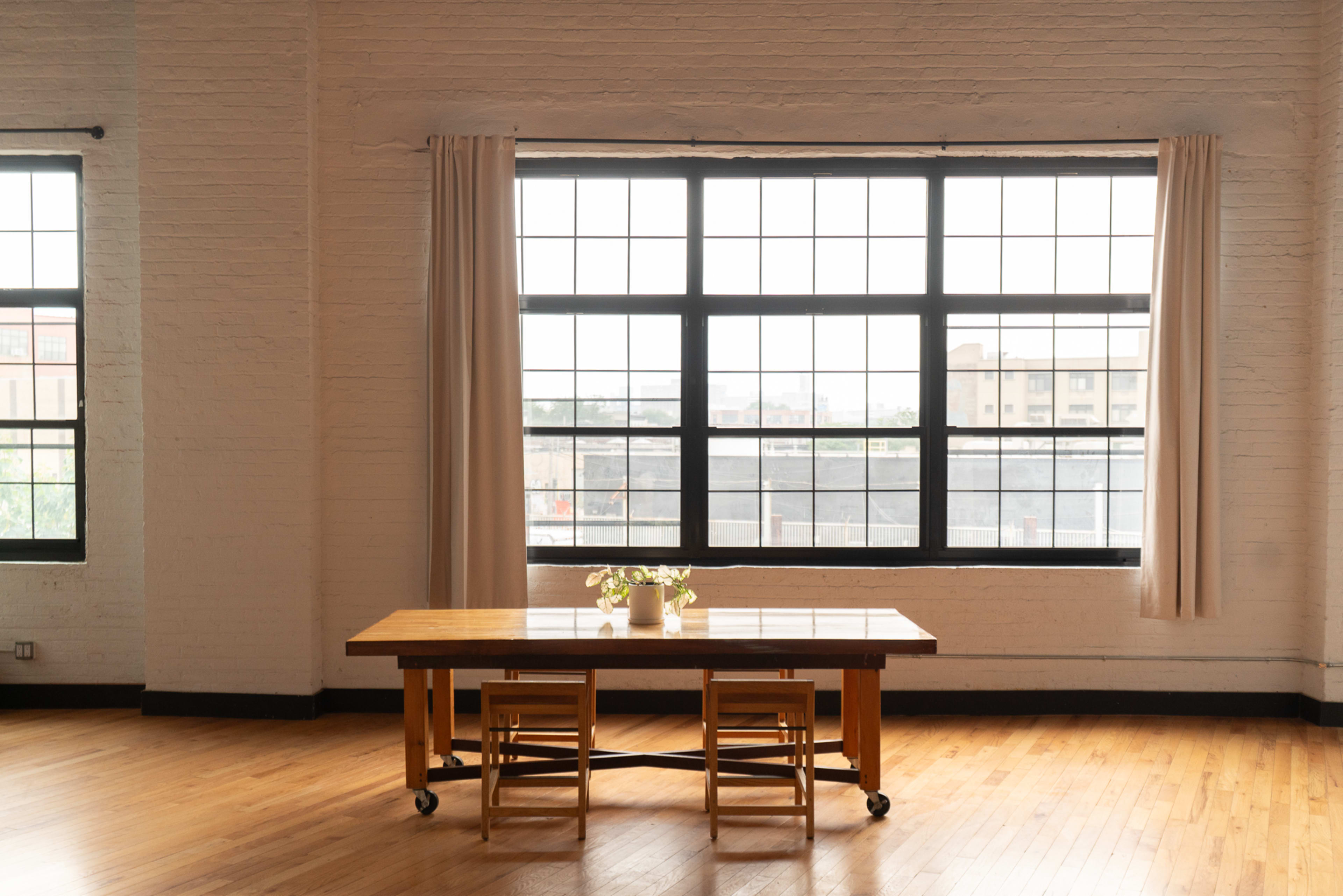 A wooden table with two chairs sits in front of large windows that allow natural light to fill the room.