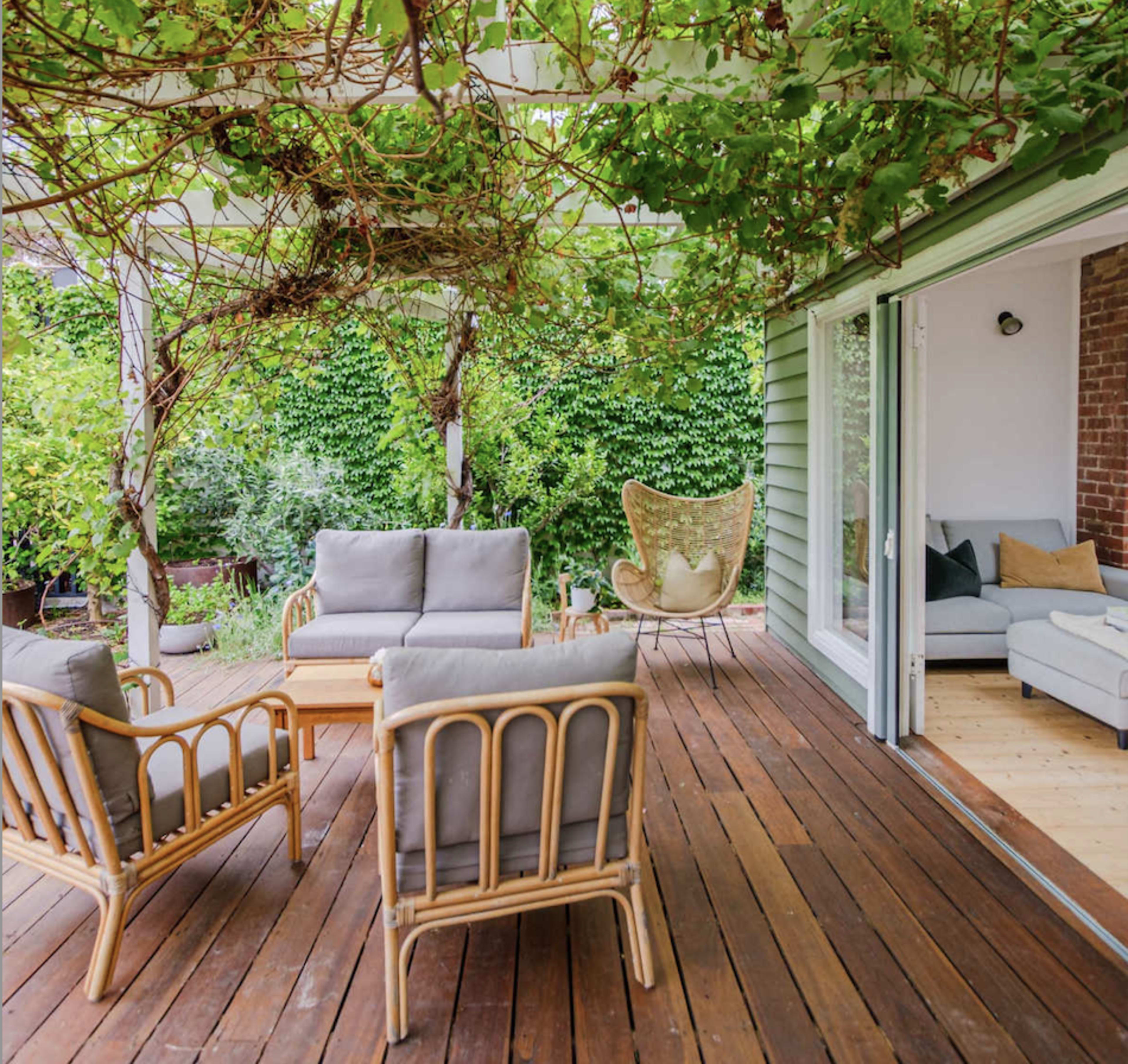 A shaded outdoor seating area with rattan furniture surrounded by lush greenery.