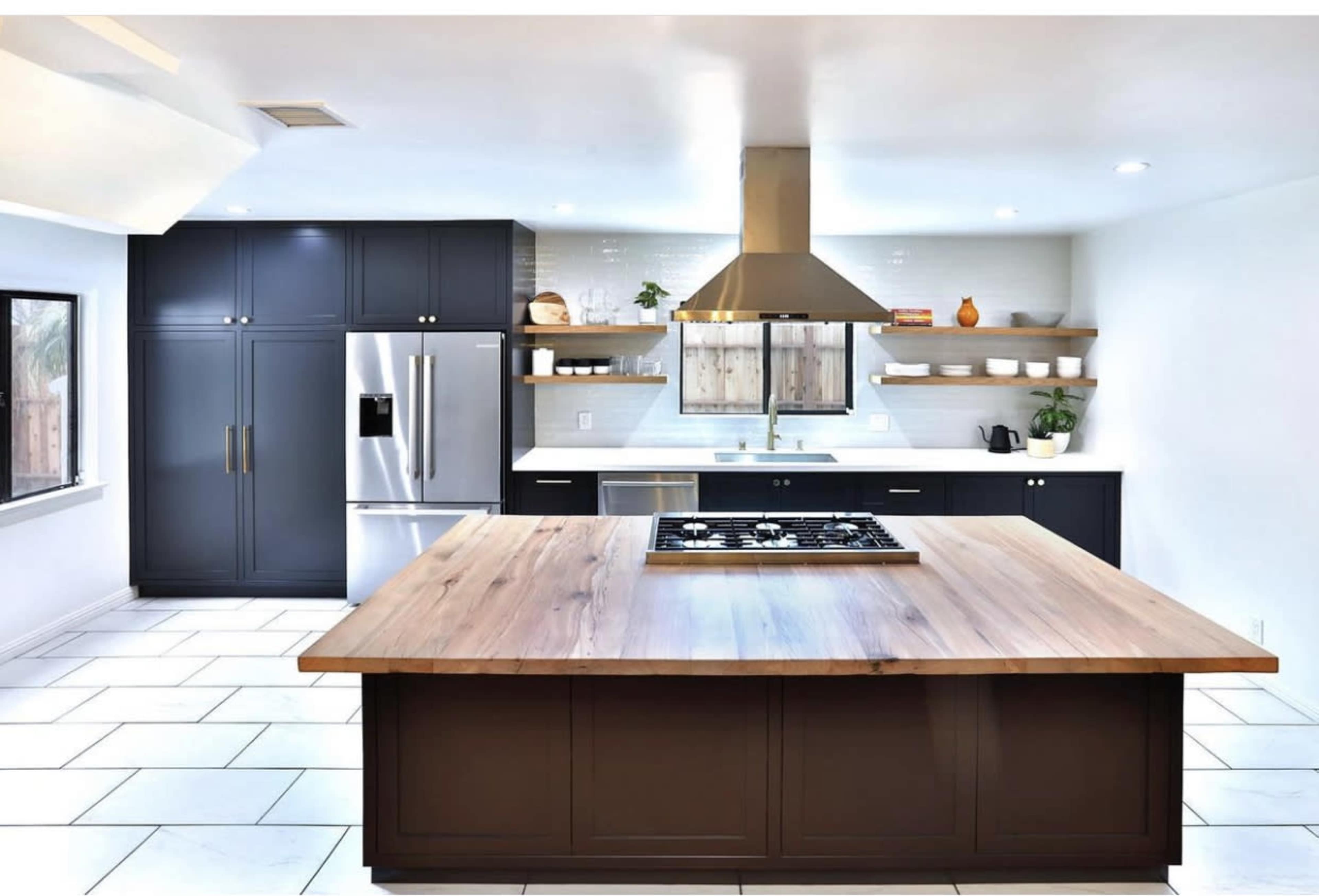 The kitchen features a large wooden island with a gas cooktop, dark cabinetry, stainless steel appliances, and open shelving.