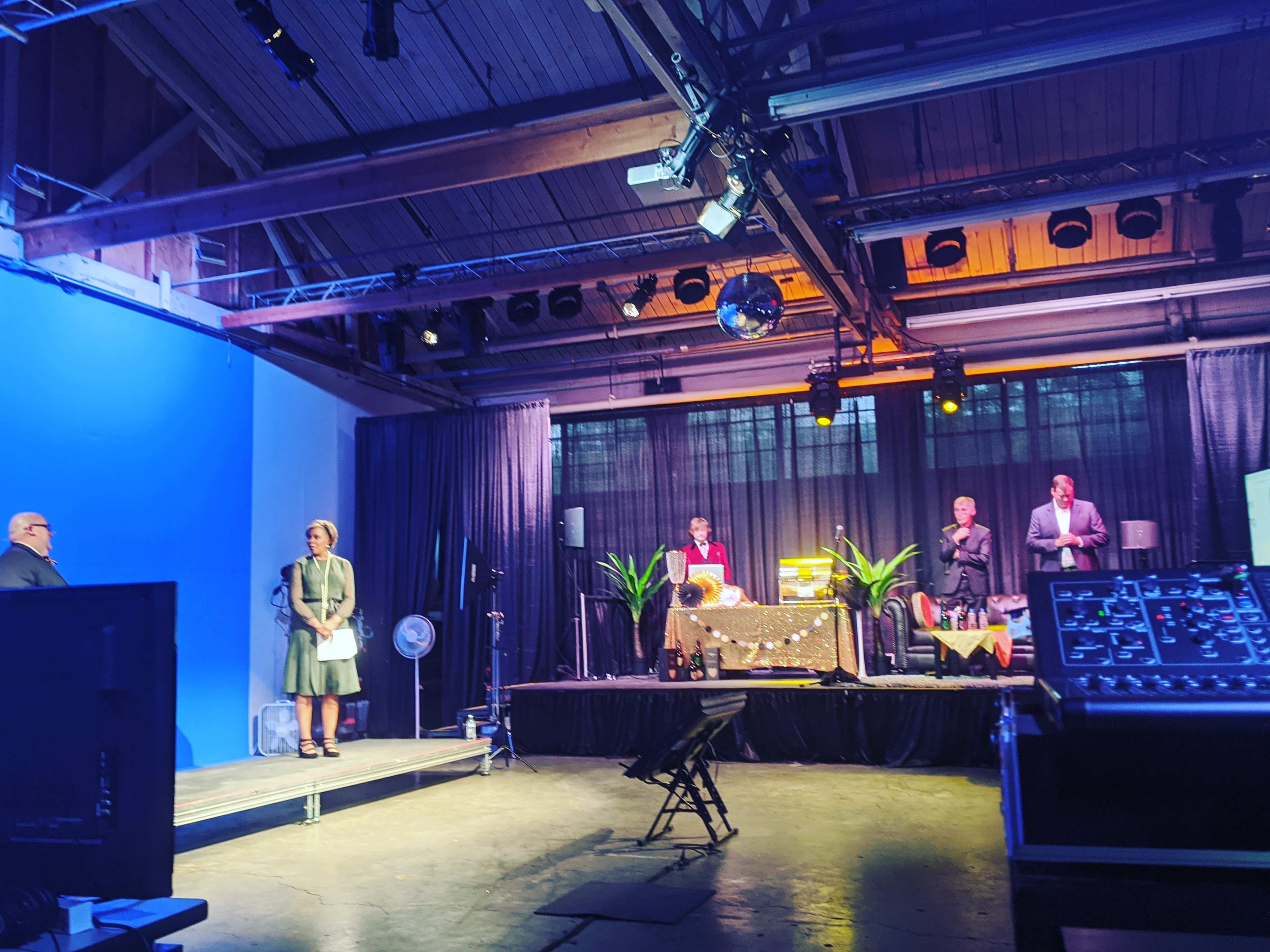 A stage setup with speakers and audience members, featuring a large screen and various lighting elements.