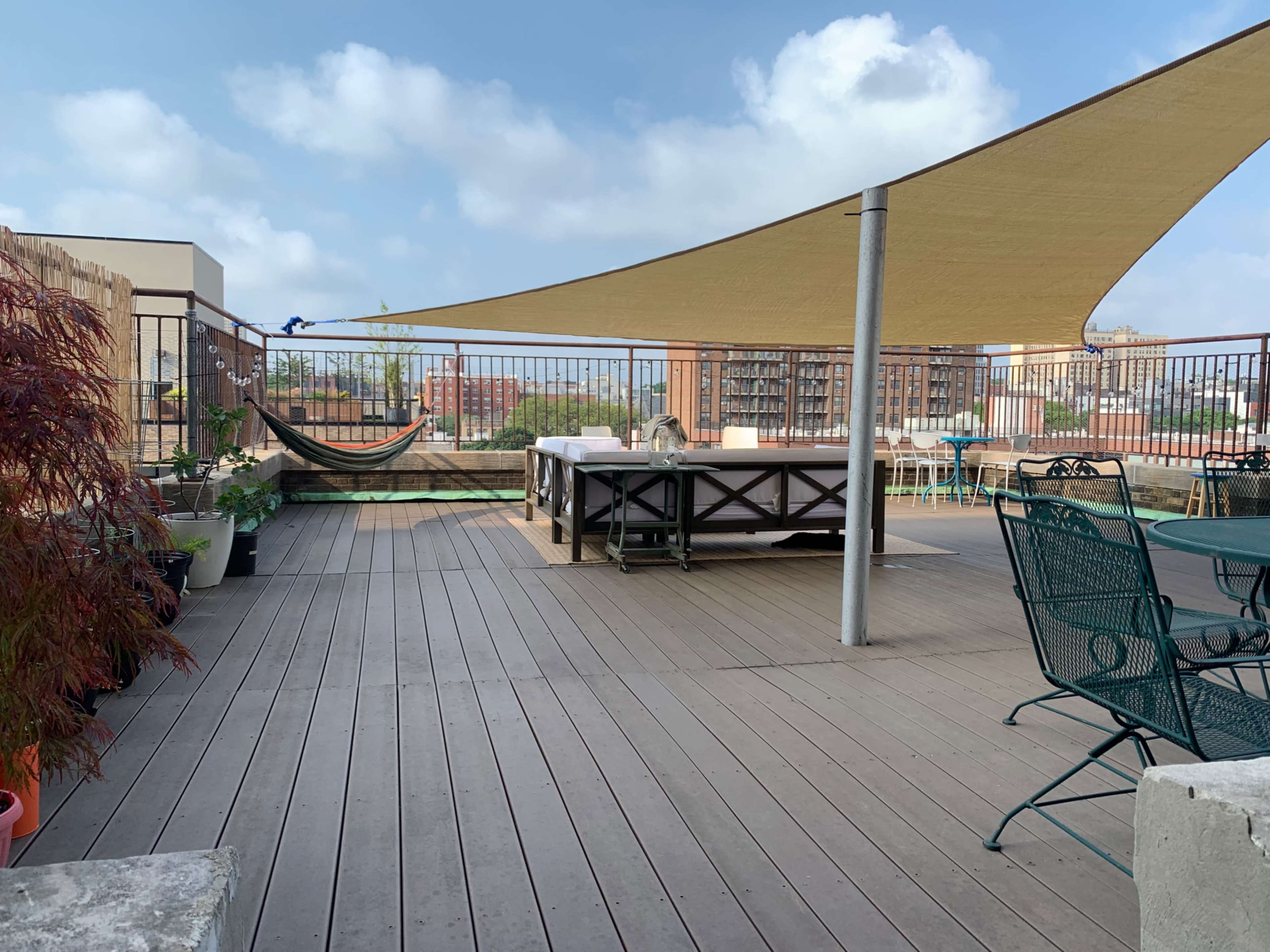 A rooftop terrace with a large shaded area, lounge seating, and a hammock.
