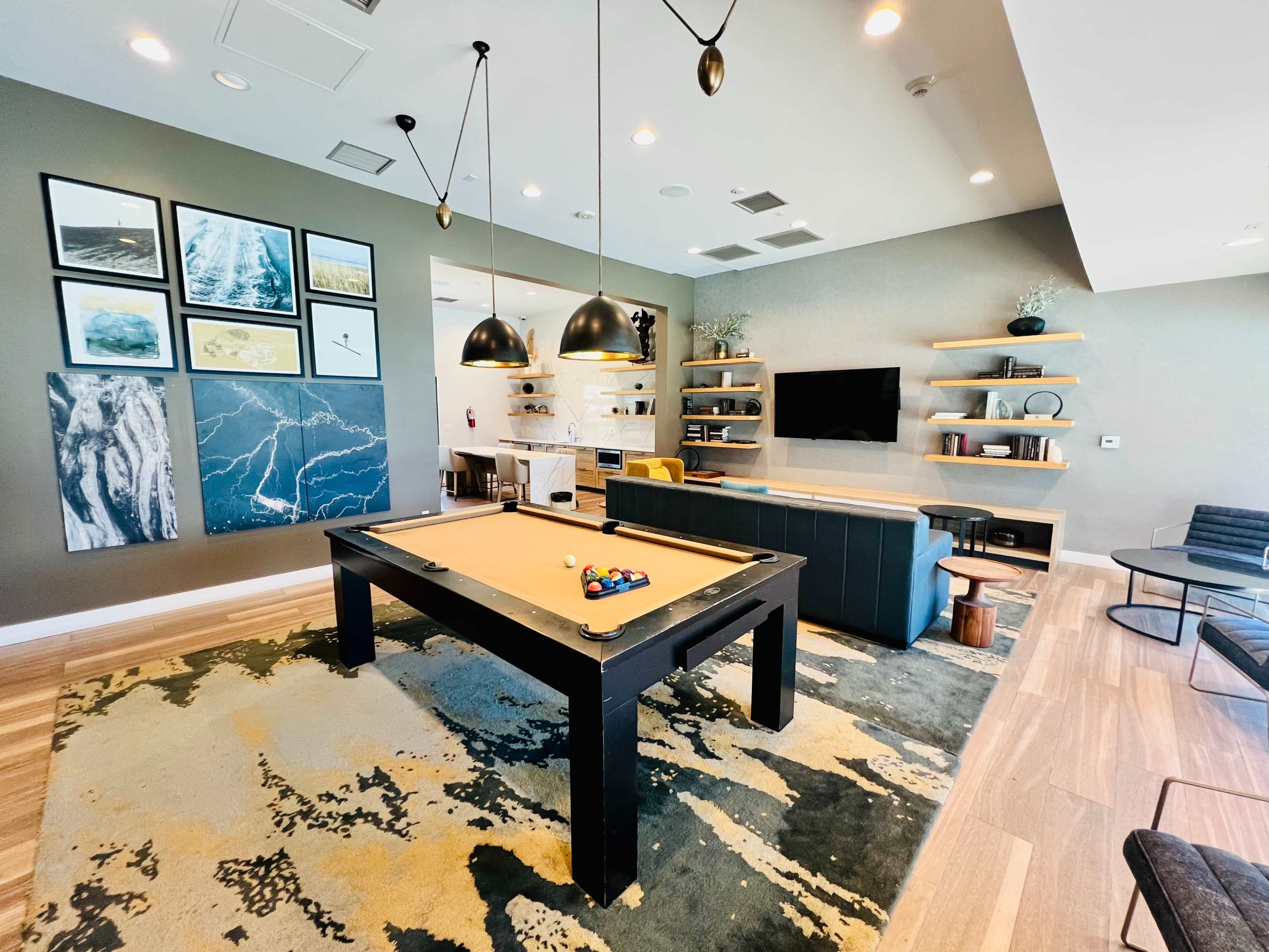 A game room with a pool table, modern seating, a television, and decorative wall art.
