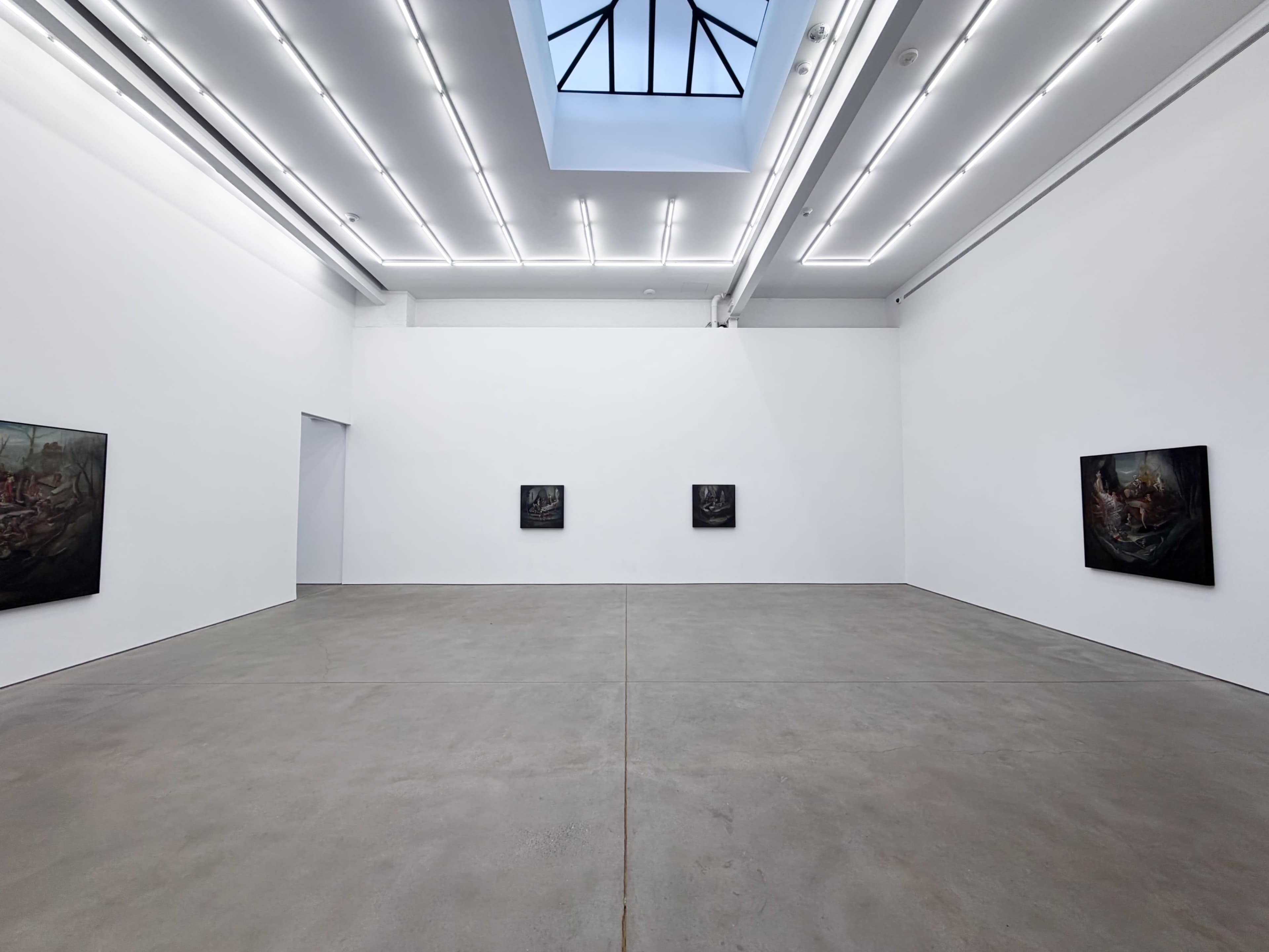 The image depicts a spacious art gallery with four dark paintings displayed on the white walls, illuminated by overhead lights and a skylight.