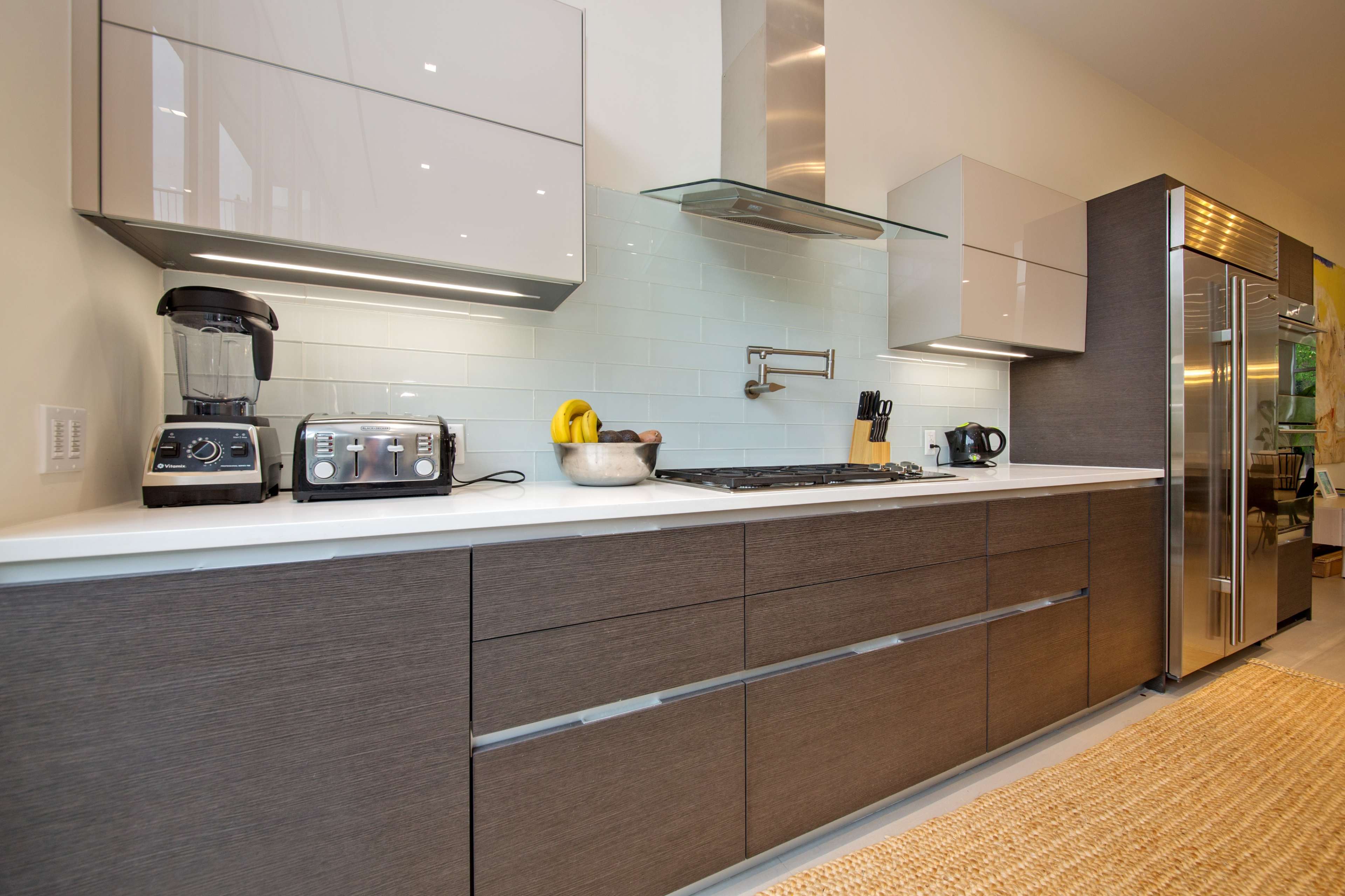 A modern kitchen featuring sleek cabinetry, a stainless steel refrigerator, a gas stove, and a blender on the countertop.
