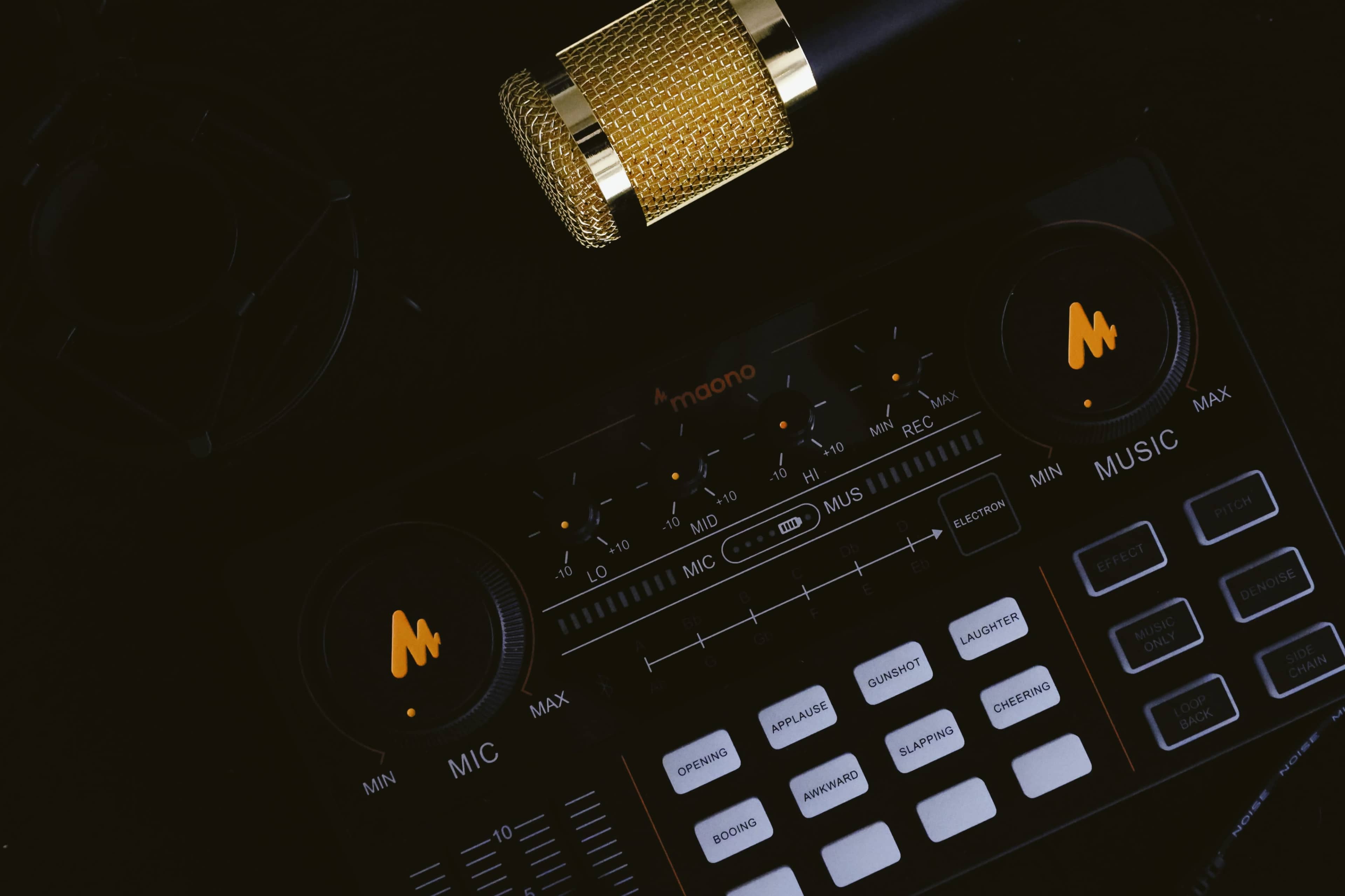 A black audio interface with control knobs and buttons, alongside a gold microphone.