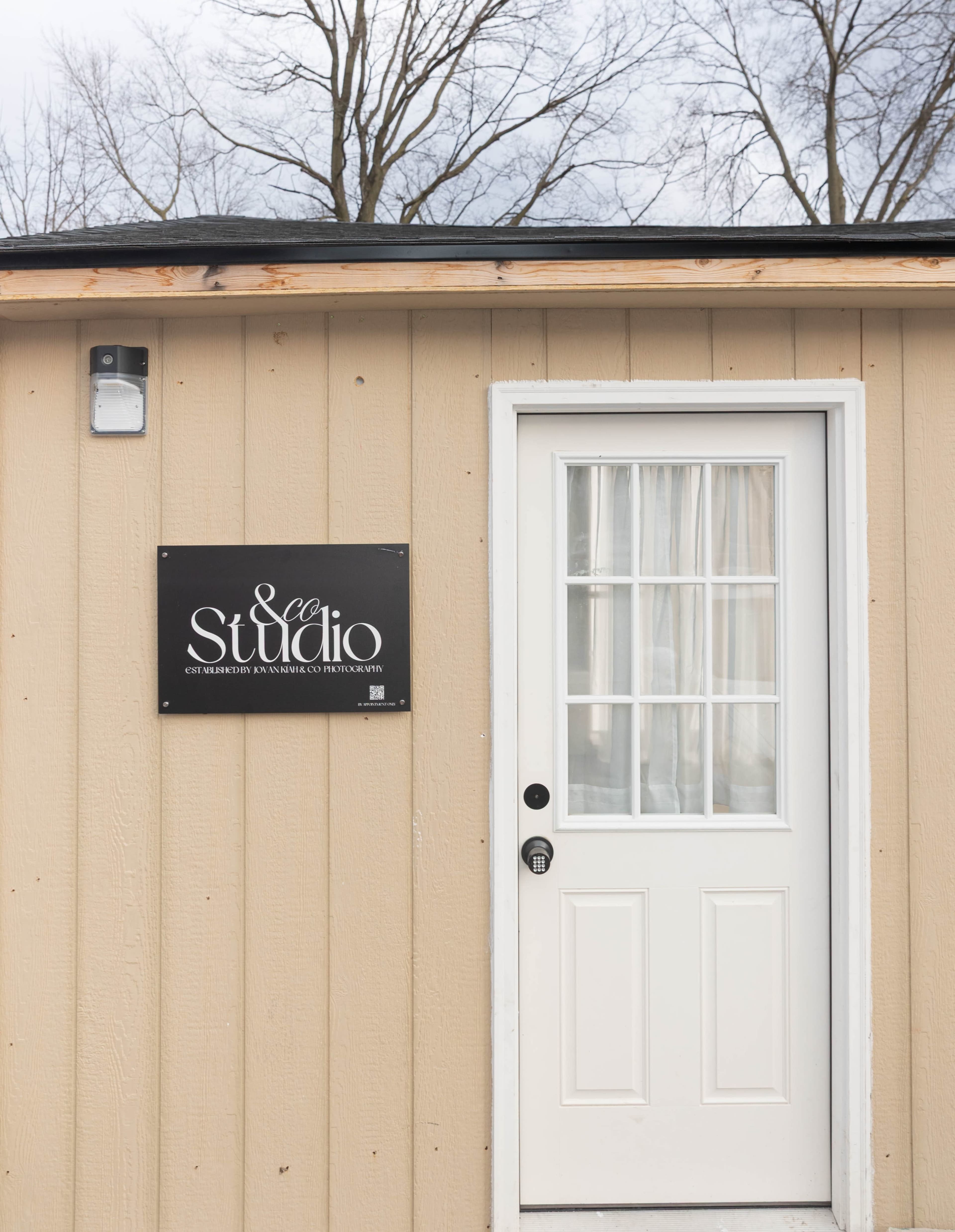 The image shows the entrance of a building with a white door and a black sign that reads "& Co Studio."