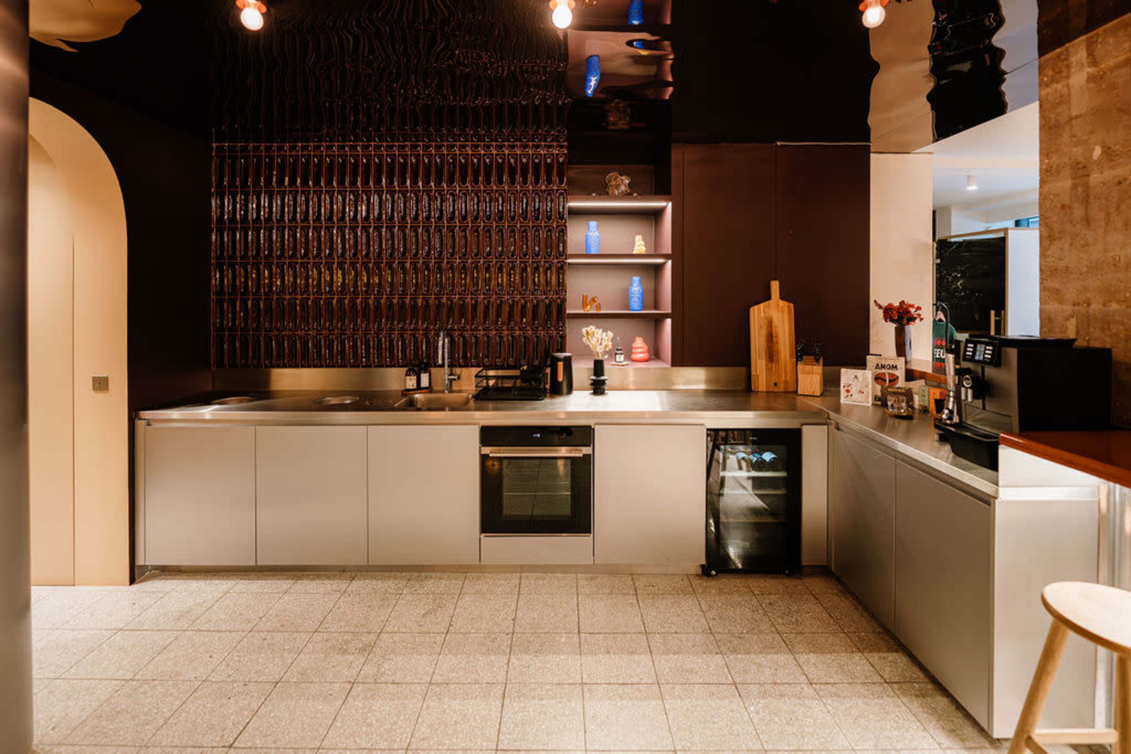 The image shows a modern kitchen with stainless steel appliances, a gray countertop, and an organized shelving unit displaying decorative items.