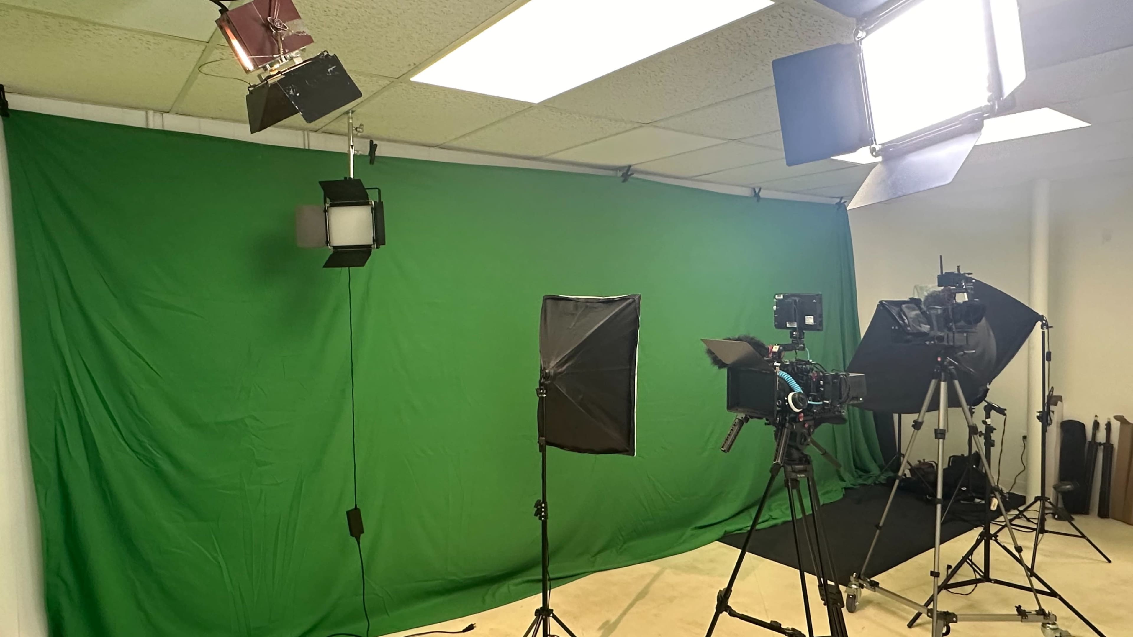 A photography studio with a green screen backdrop and various lighting setups.
