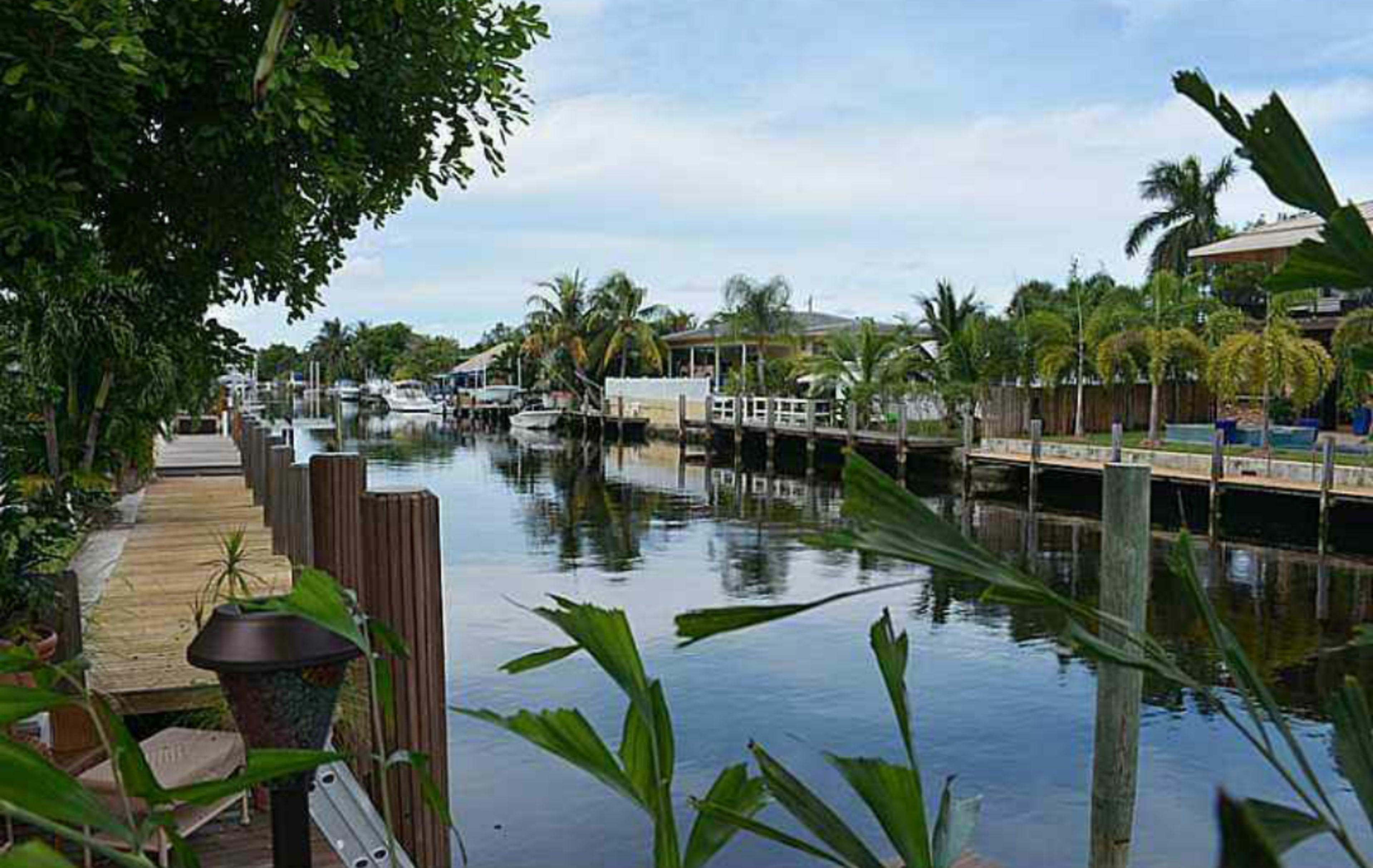 A calm canal lined with boats and residential properties under a clear sky.