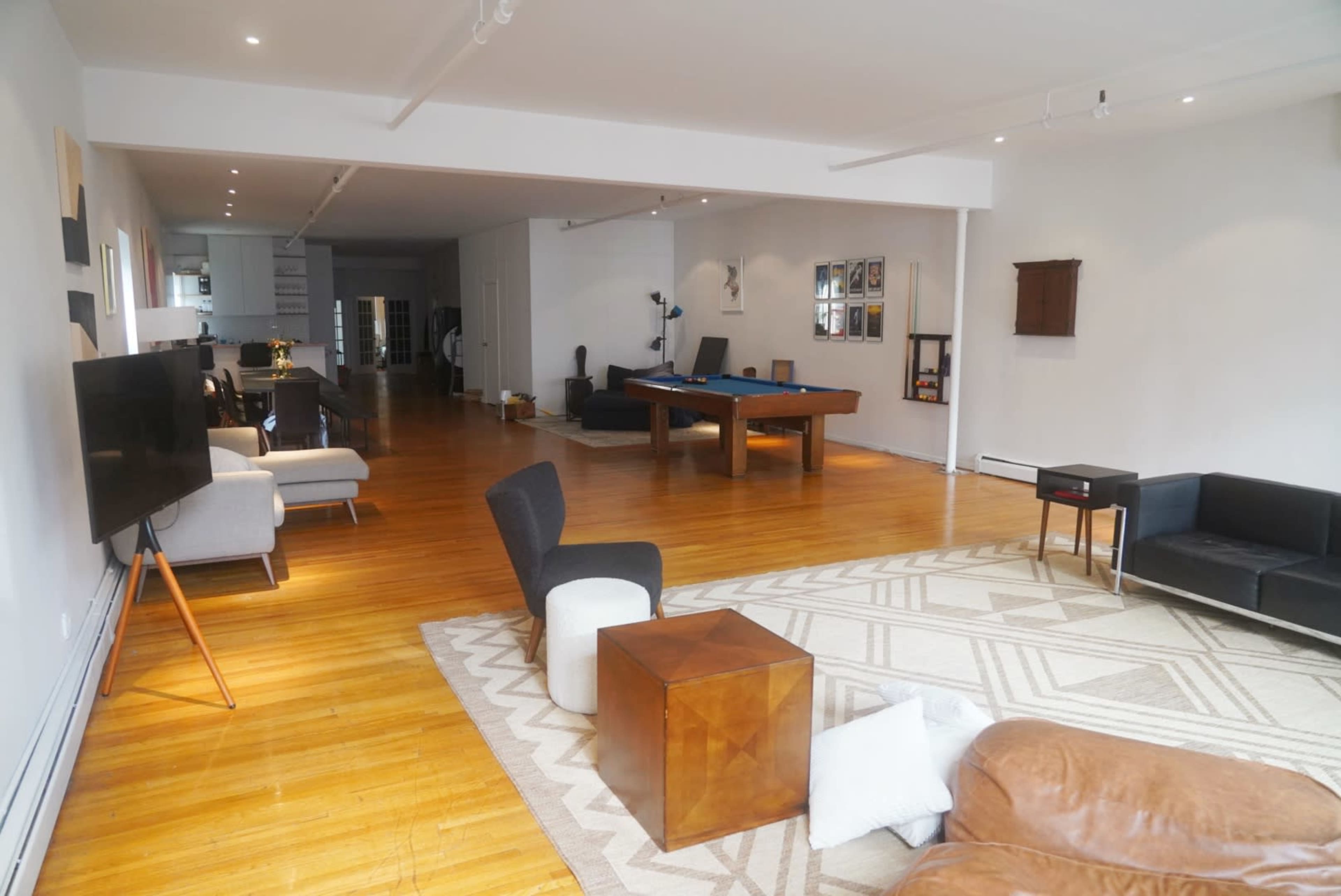 The spacious interior features hardwood flooring, a mix of seating arrangements, and a pool table in a well-lit area.