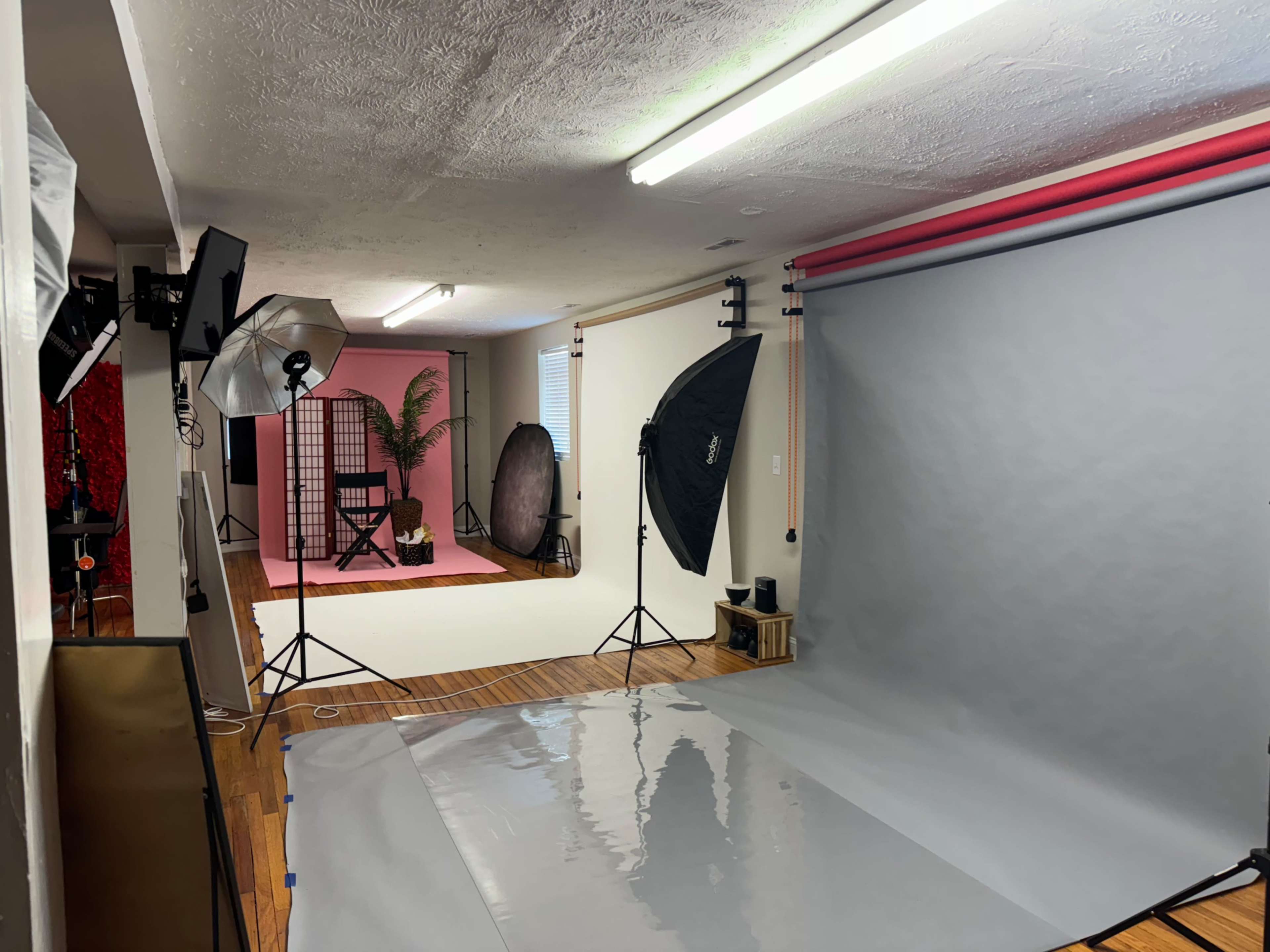 A photography studio setup with various backdrops, lighting equipment, and a professional chair positioned against colored walls.