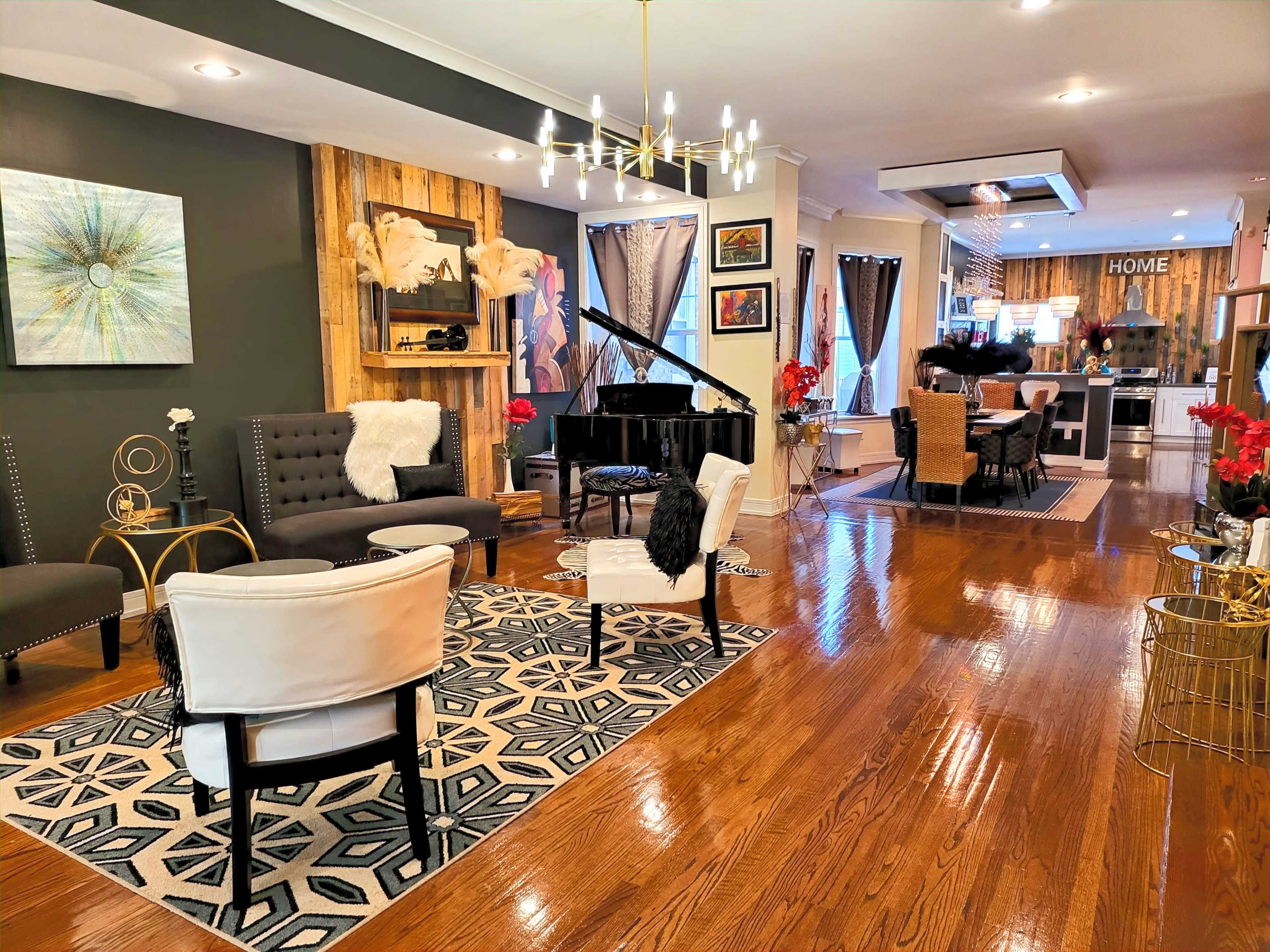 A spacious living area features a black grand piano, assorted seating, and a decorative fireplace with contemporary art on the walls.