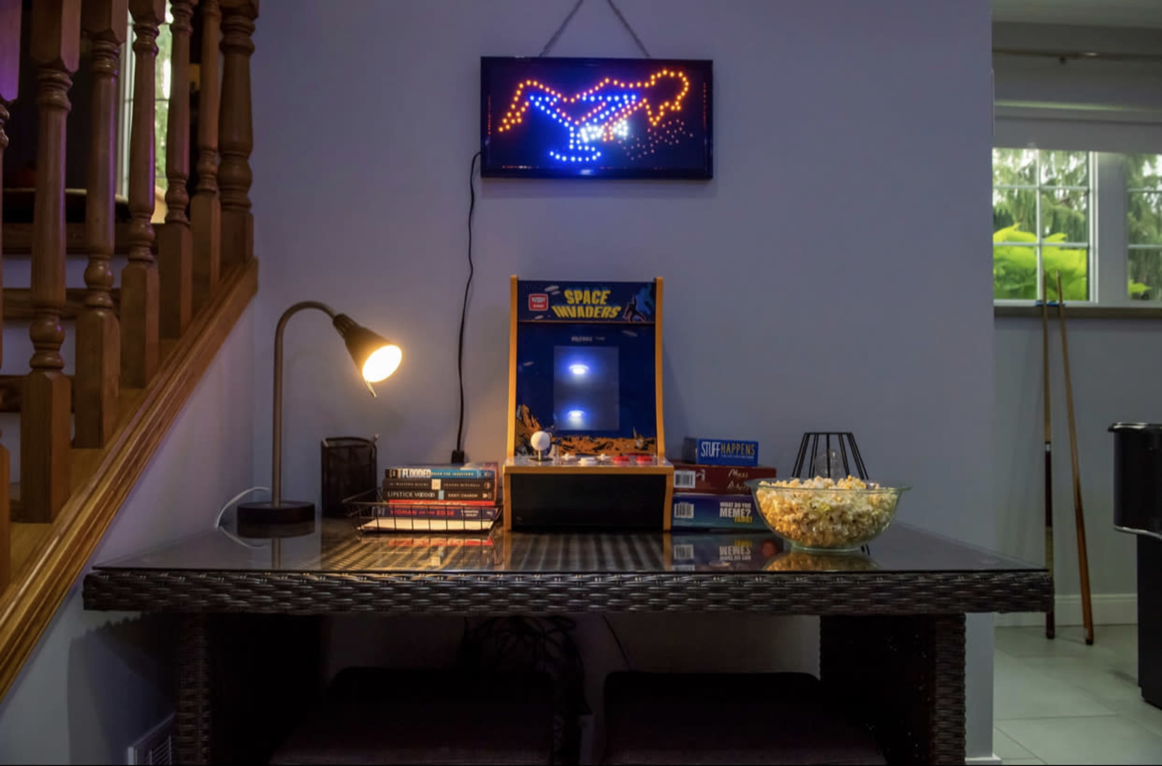 A cozy entertainment area features a retro arcade machine, a bowl of popcorn, and a glowing wall display above a table.