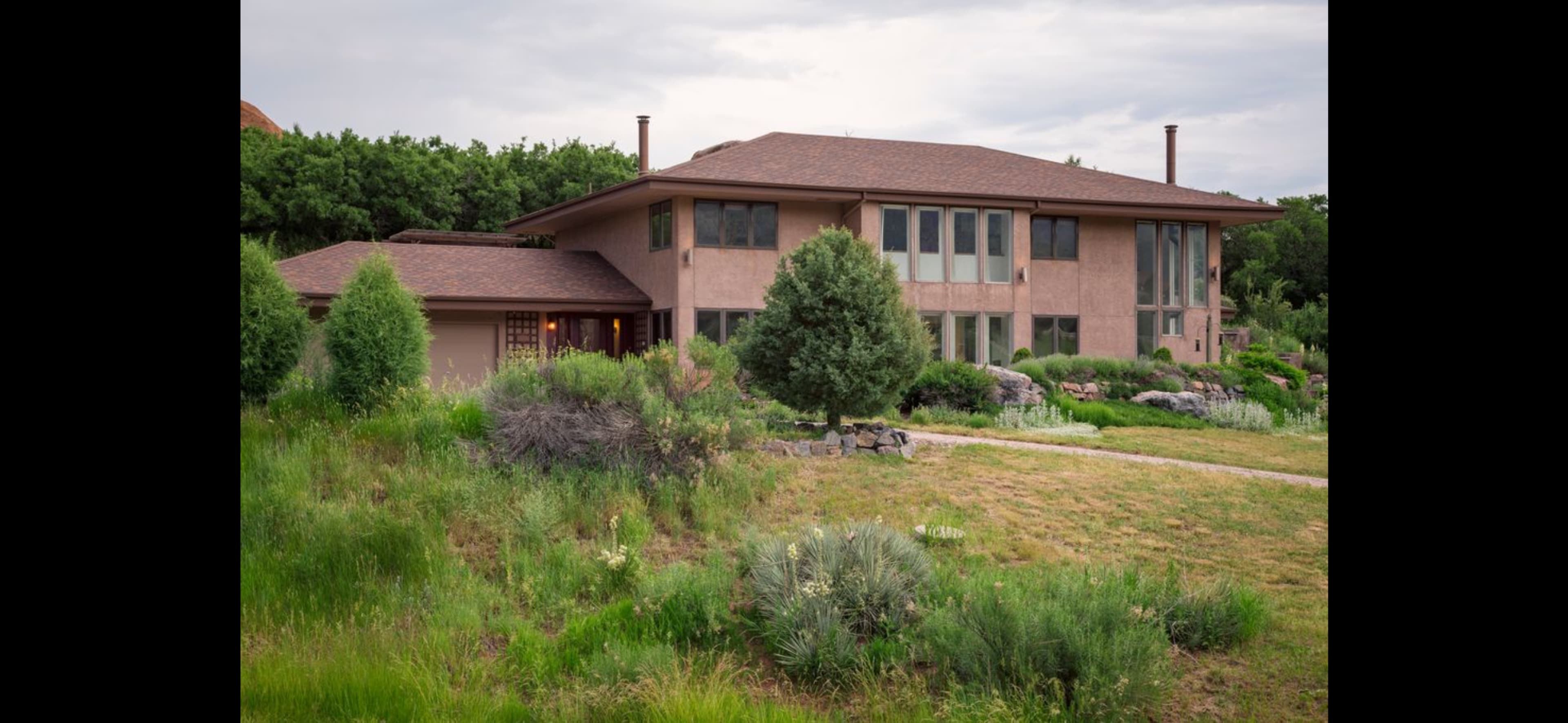 A modern, two-story home is surrounded by lush greenery and a well-maintained garden.