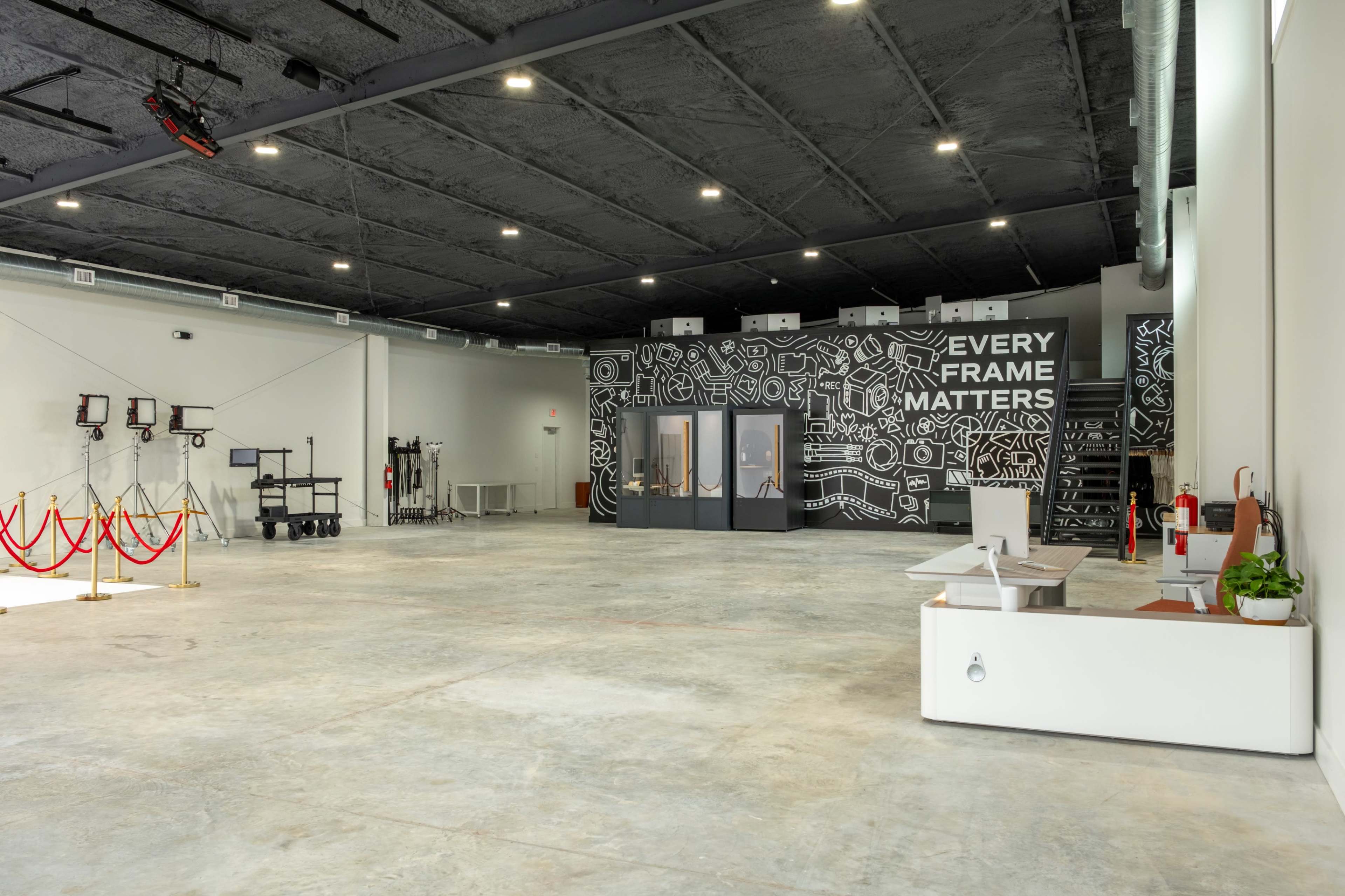 The image shows a large, empty studio space with concrete floors and a wall mural that reads "EVERY FRAME MATTERS."
