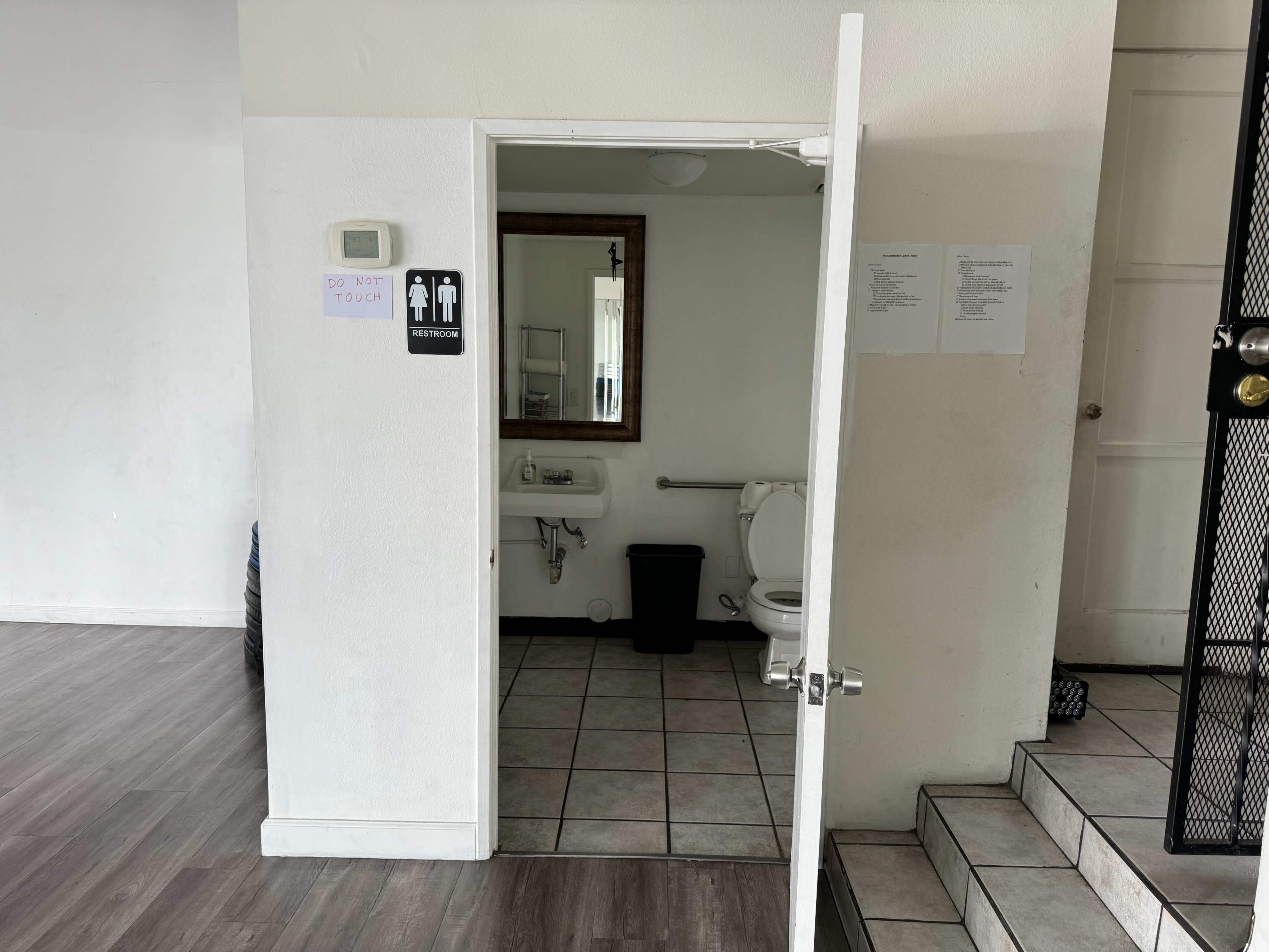 An open restroom door with a sign indicating "Restroom" and a visible toilet and sink inside.