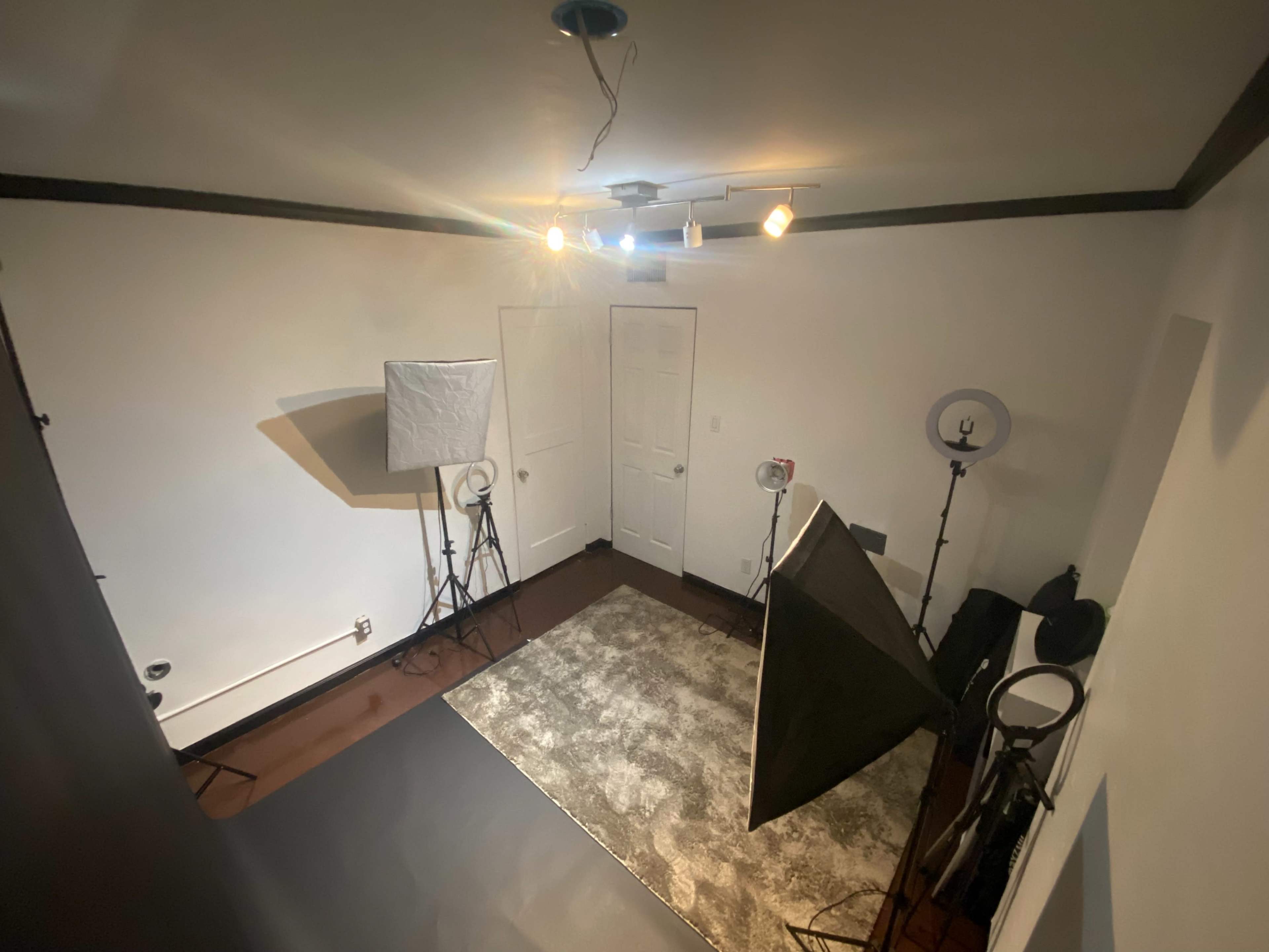 A well-lit empty studio space with lighting equipment and a rug.