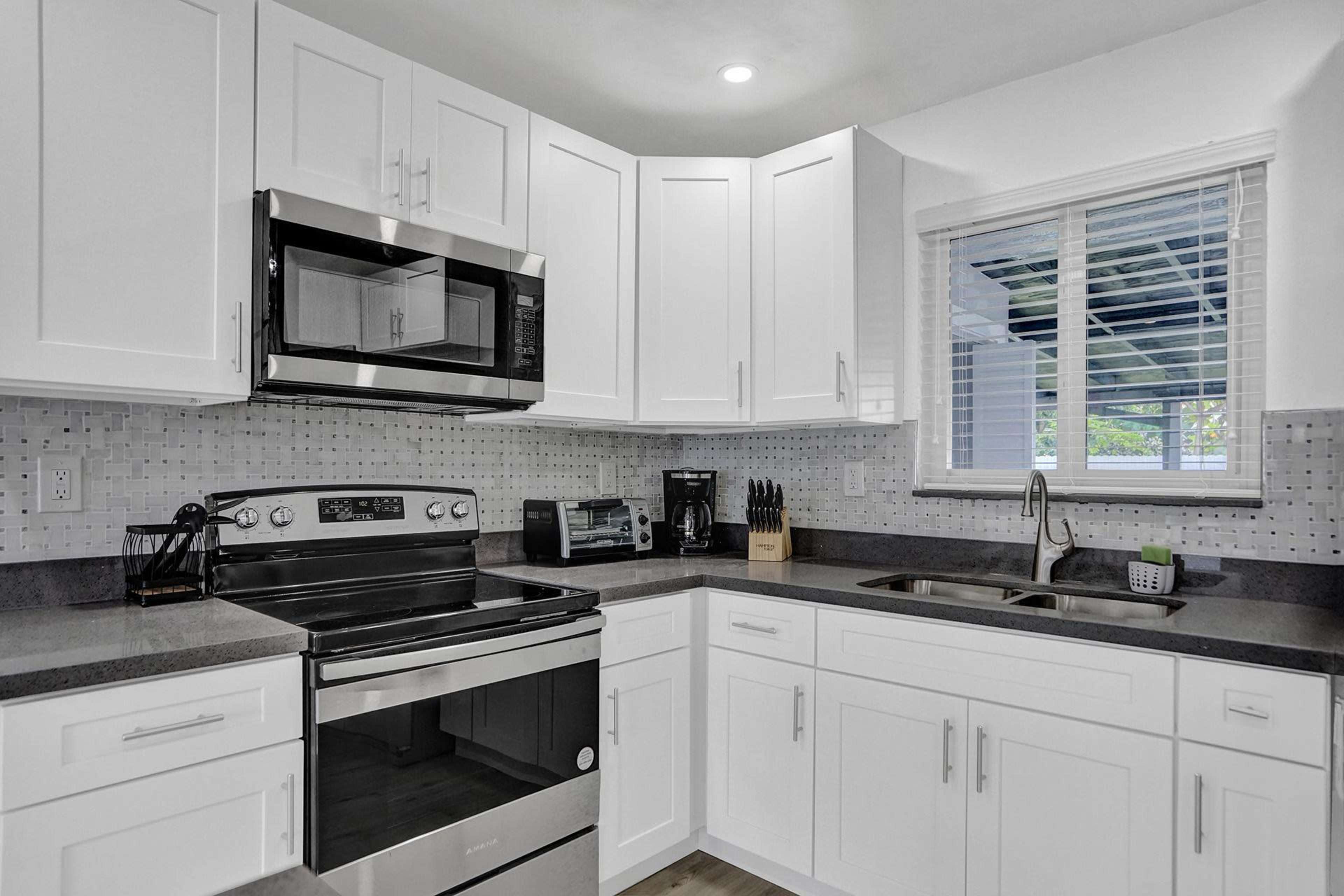 A modern kitchen with white cabinetry, stainless steel appliances, and a gray countertop.