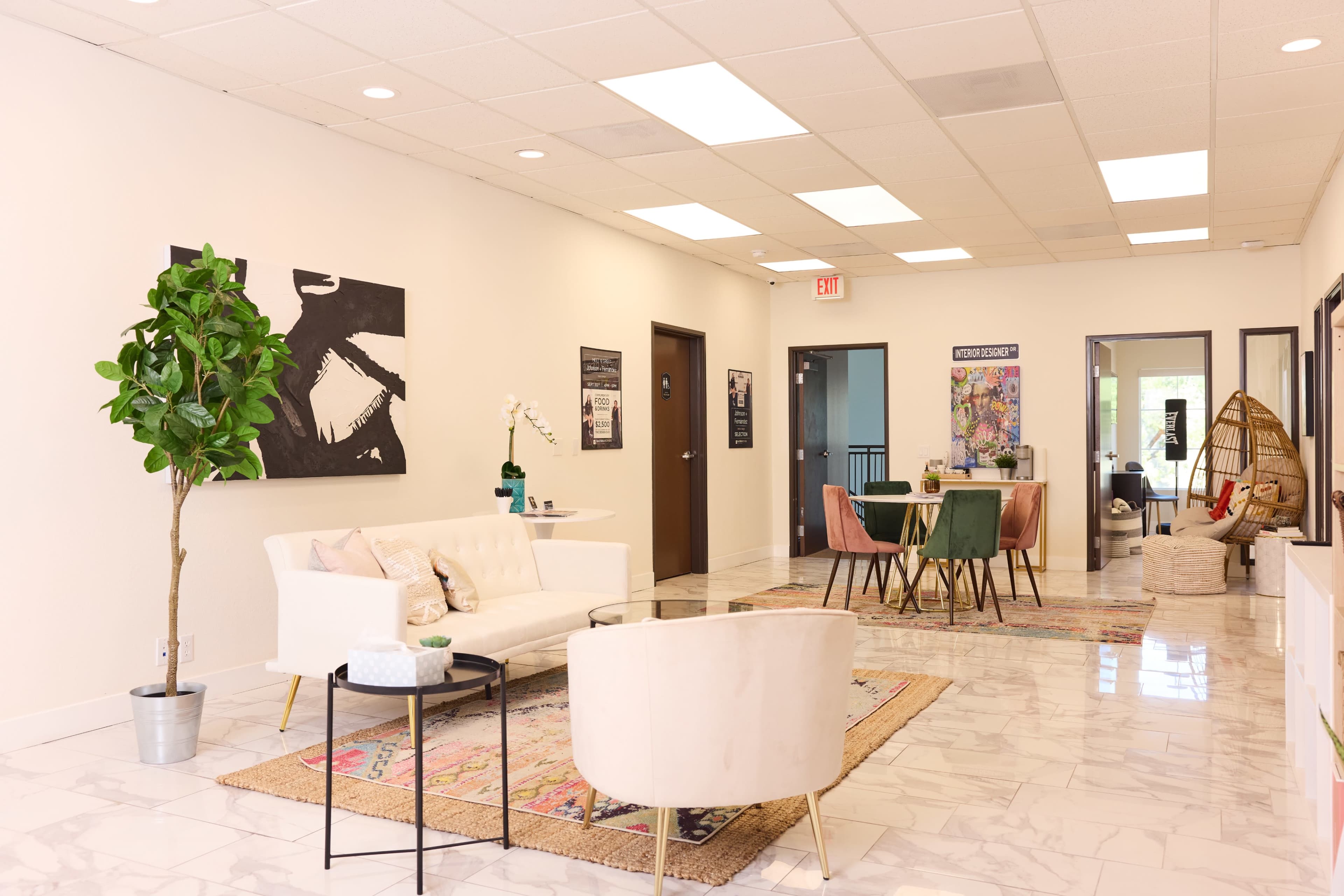 A spacious interior features a white sofa and decorative plants along with a dining area and various artworks on the walls.