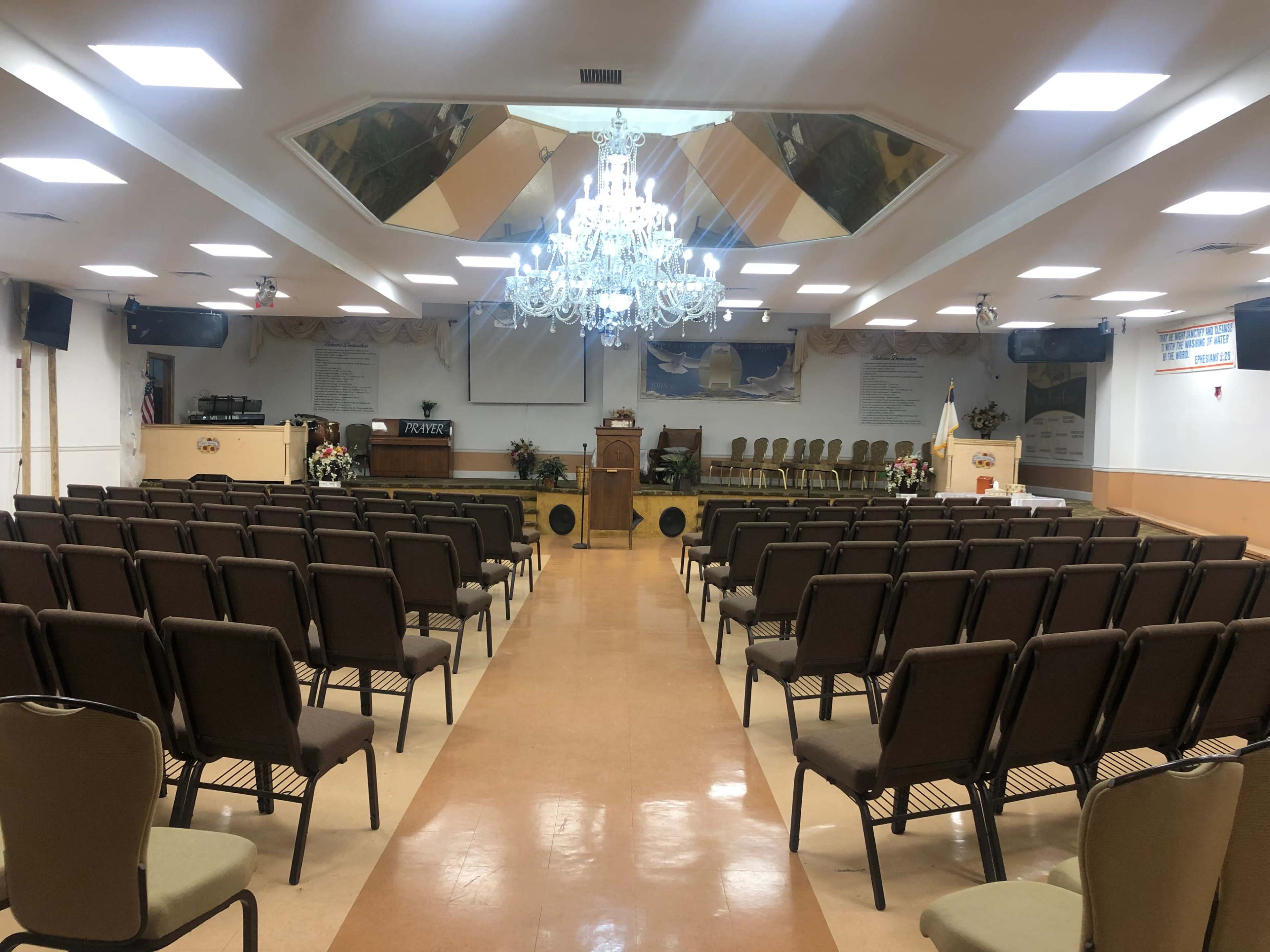 A spacious, empty auditorium with rows of chairs facing a stage adorned with a podium and decorative elements.