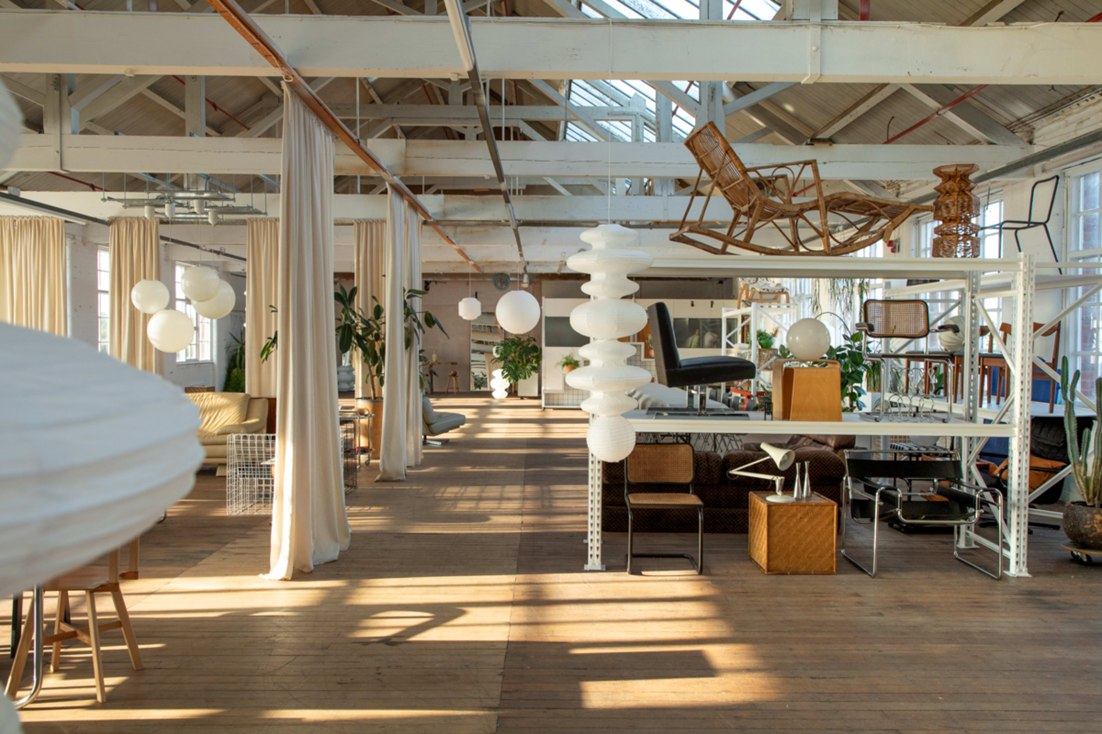 The image shows a spacious, well-lit interior of a vintage-style furniture showroom with various seating arrangements and decorative items.