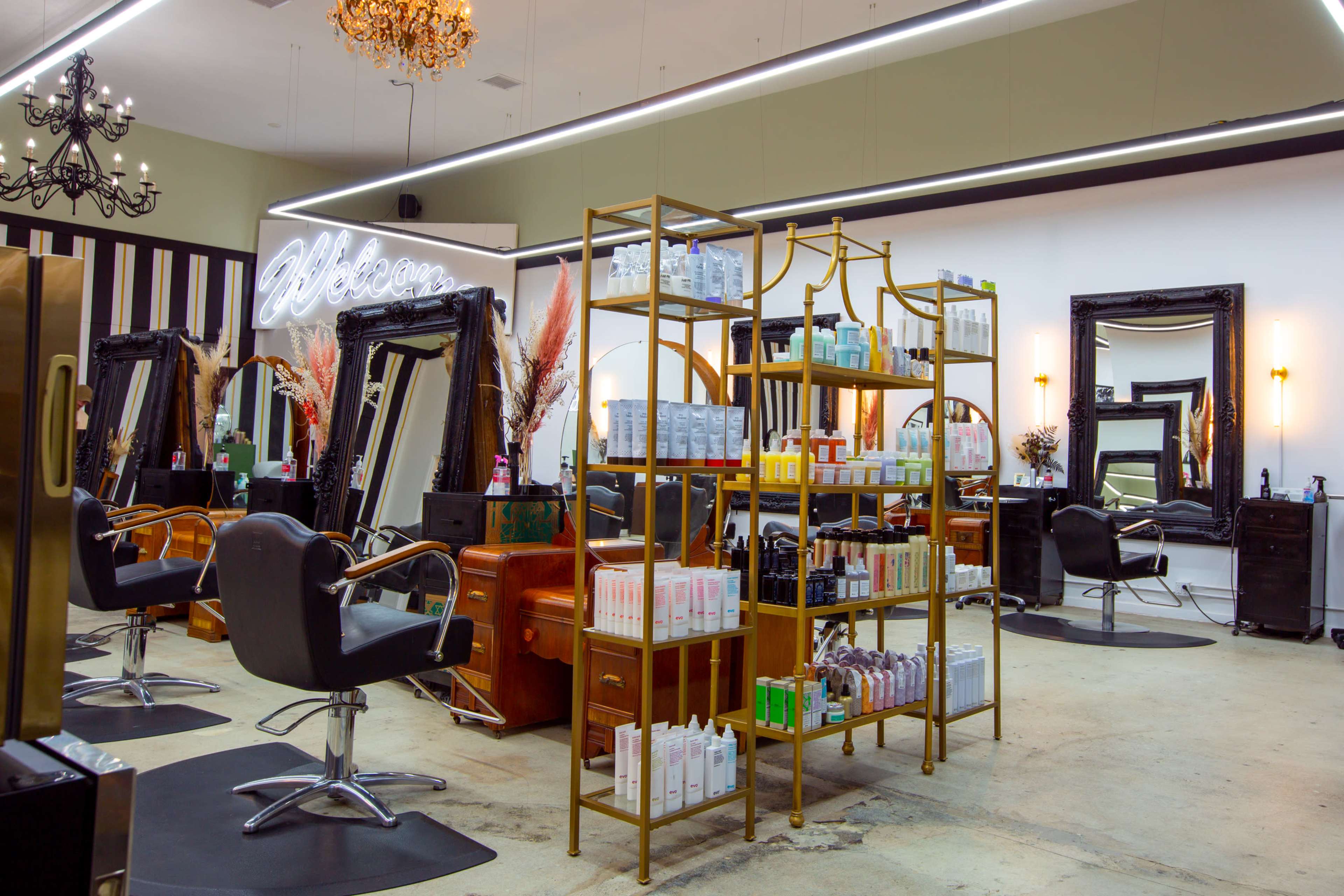 A modern salon interior with multiple styling stations, a product display rack, and ornate mirrors.