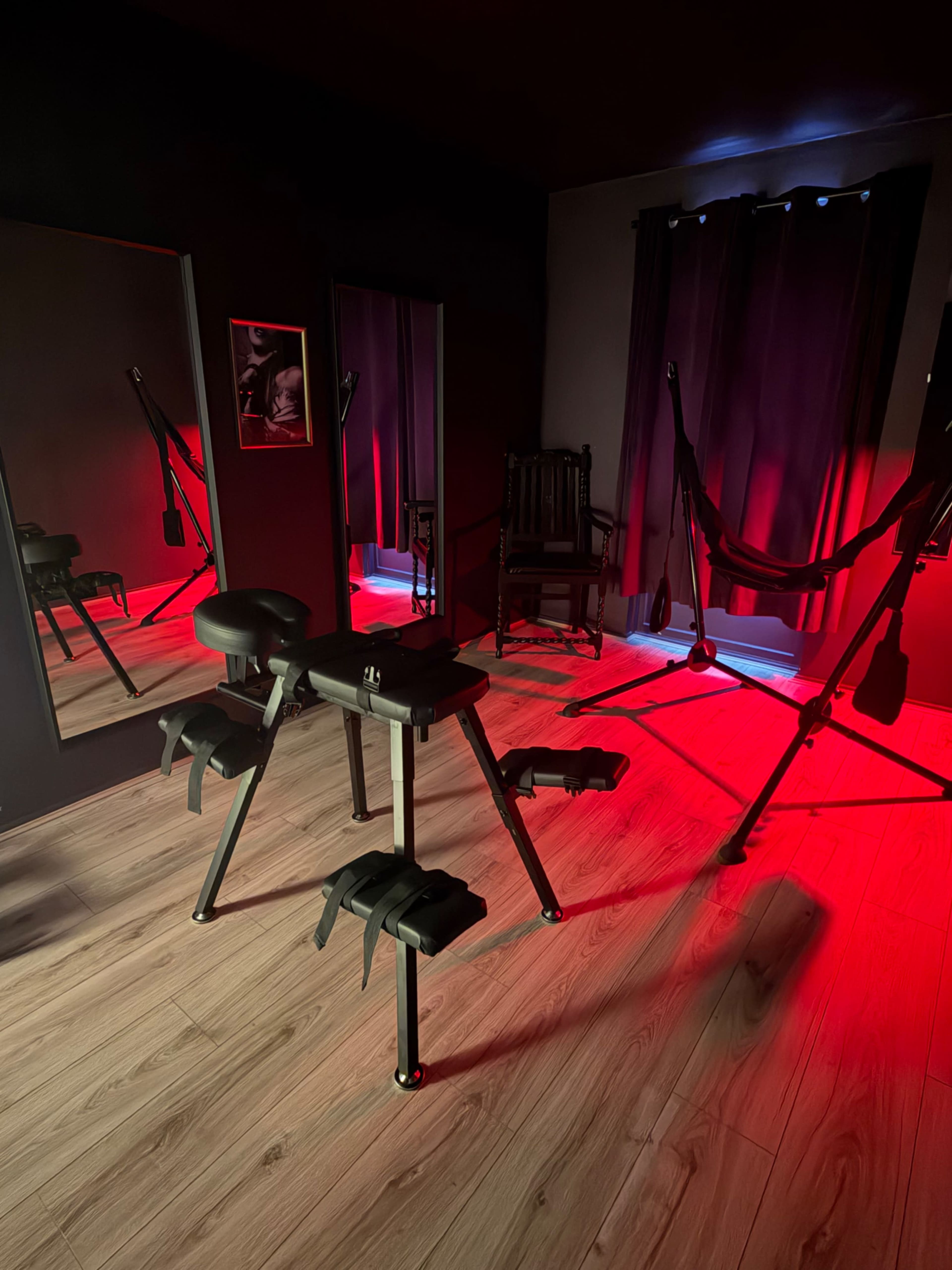 The room features exercise equipment, two mirrors, and a hammock, all illuminated by red lighting.