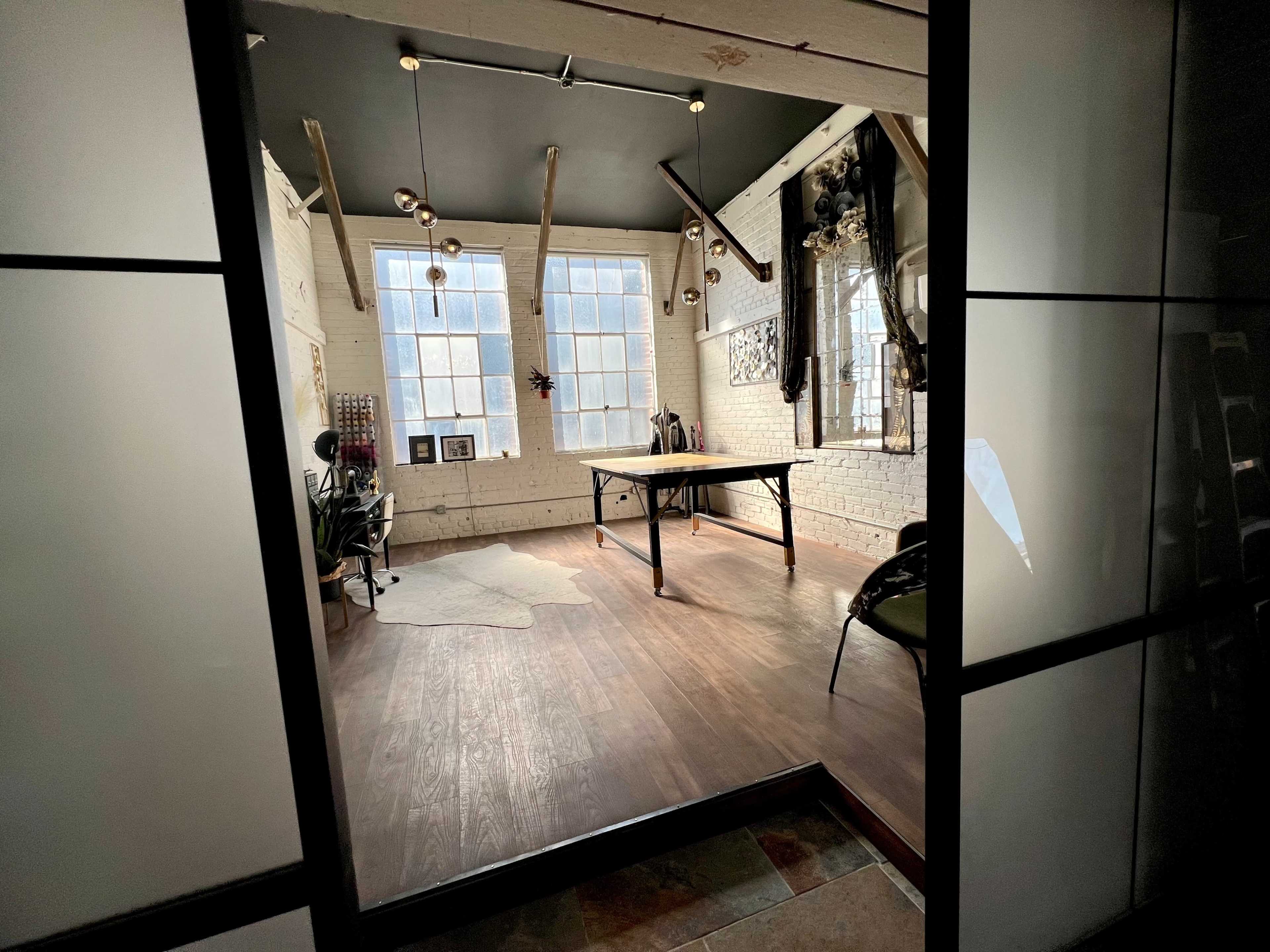 A workspace with large windows, a table in the center, and various decorative elements on the walls.