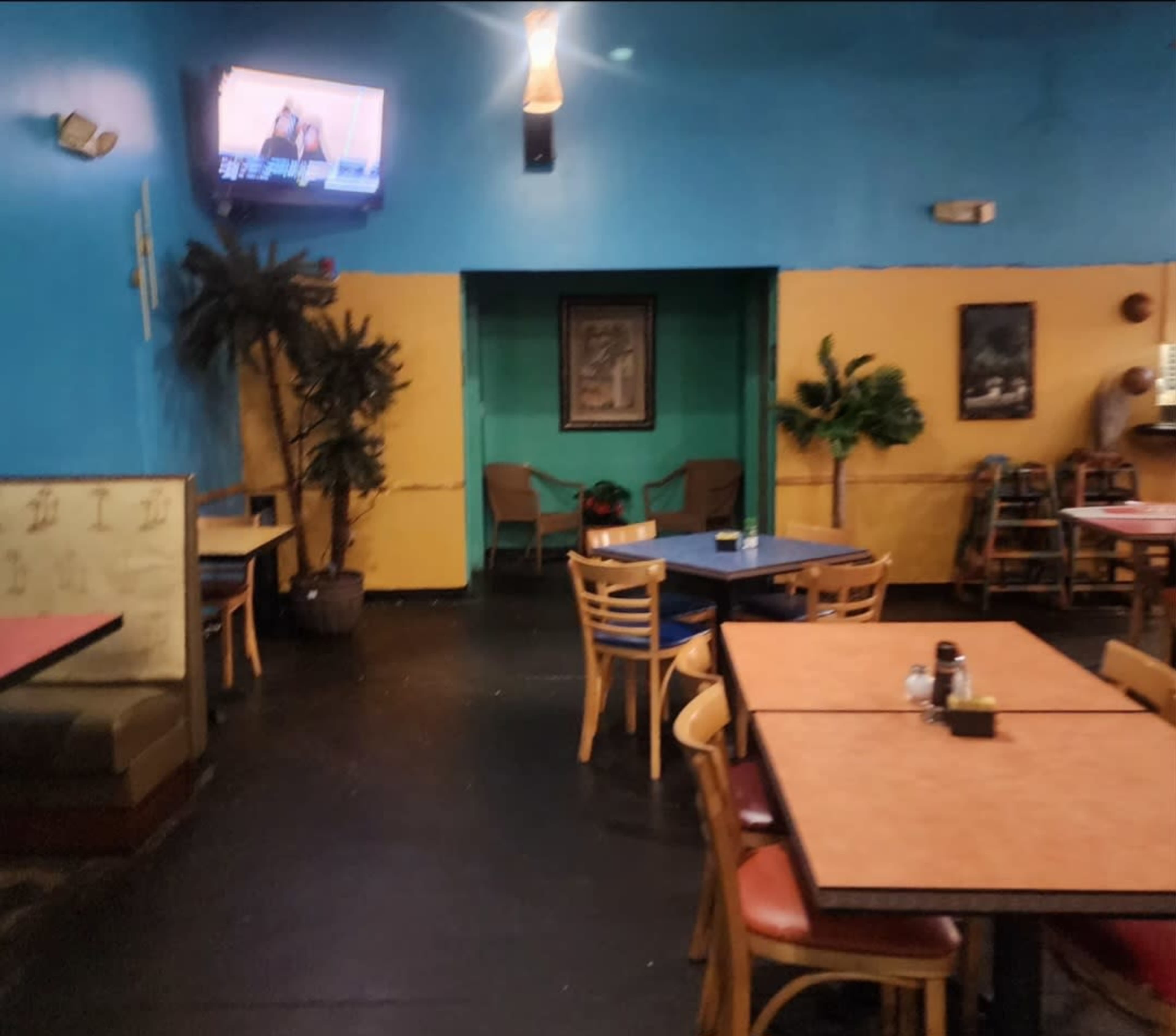 The image shows the interior of a casual restaurant with colorful walls and multiple tables arranged throughout the space.