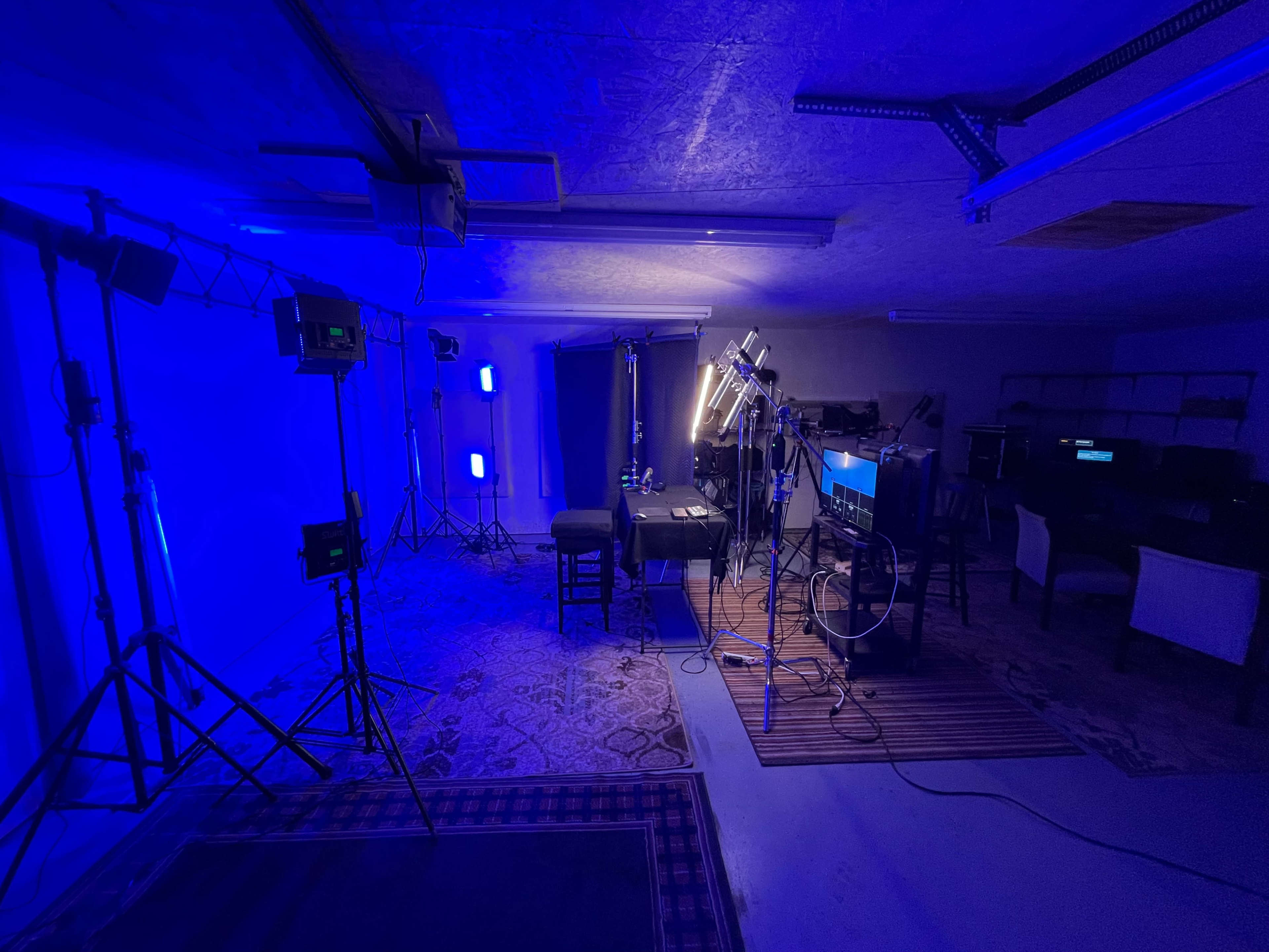 A dimly lit studio setup with various lighting equipment, a table in the center, and a backdrop.