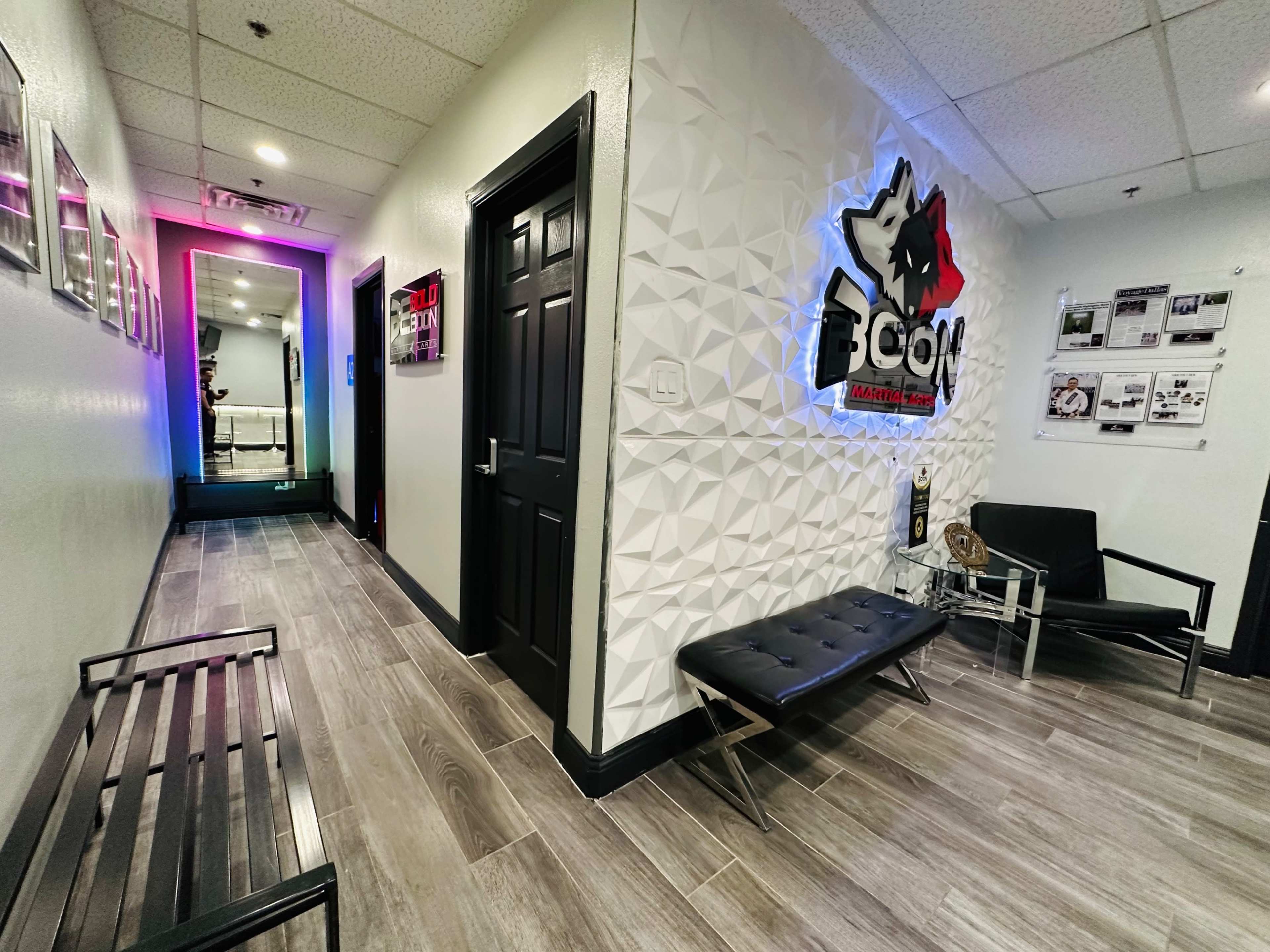 A well-lit corridor with textured walls, a bench on the left, and a door at the end leading to another room.
