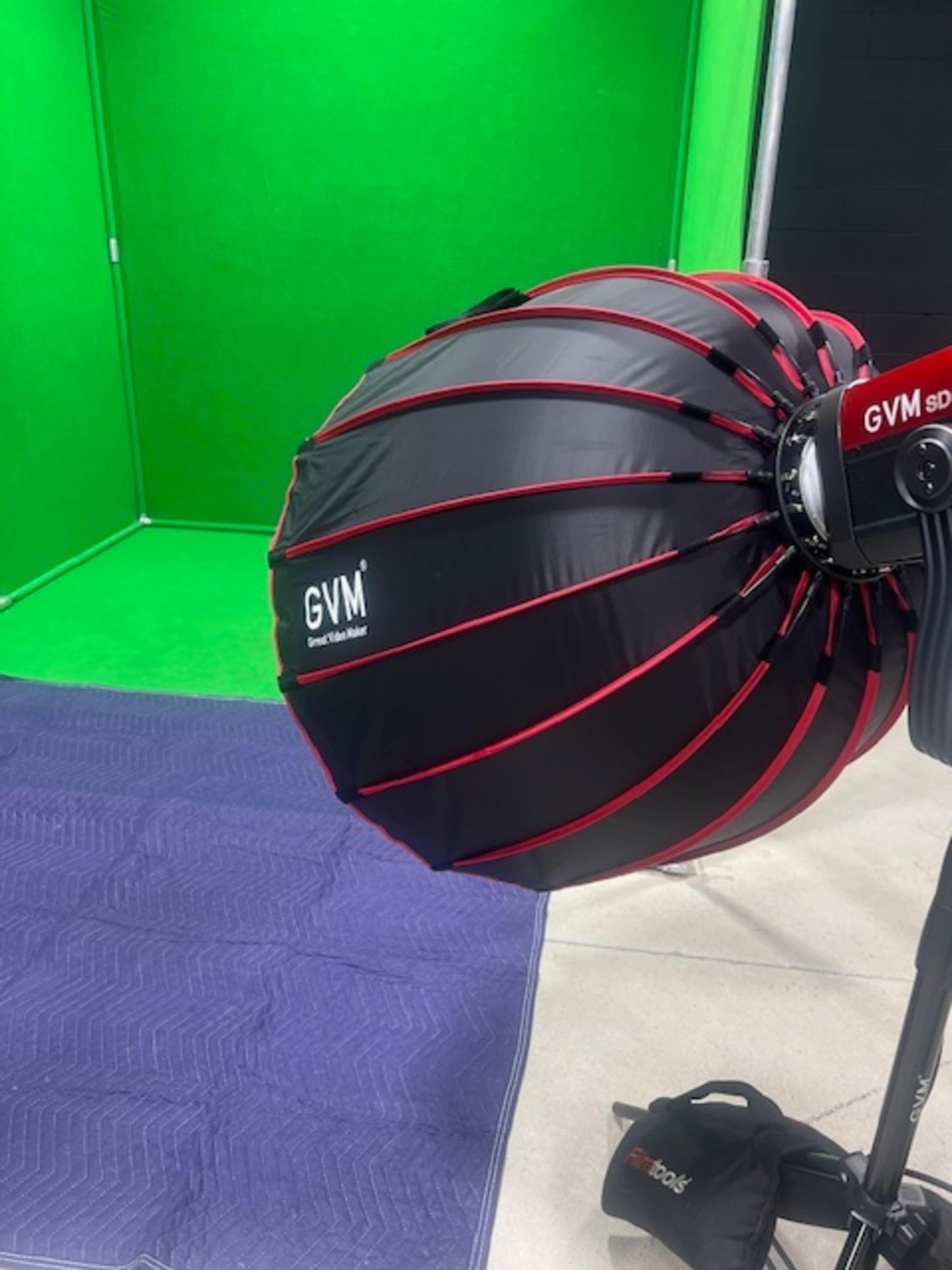 The image shows a large softbox umbrella attached to a lighting stand in front of a green screen backdrop.