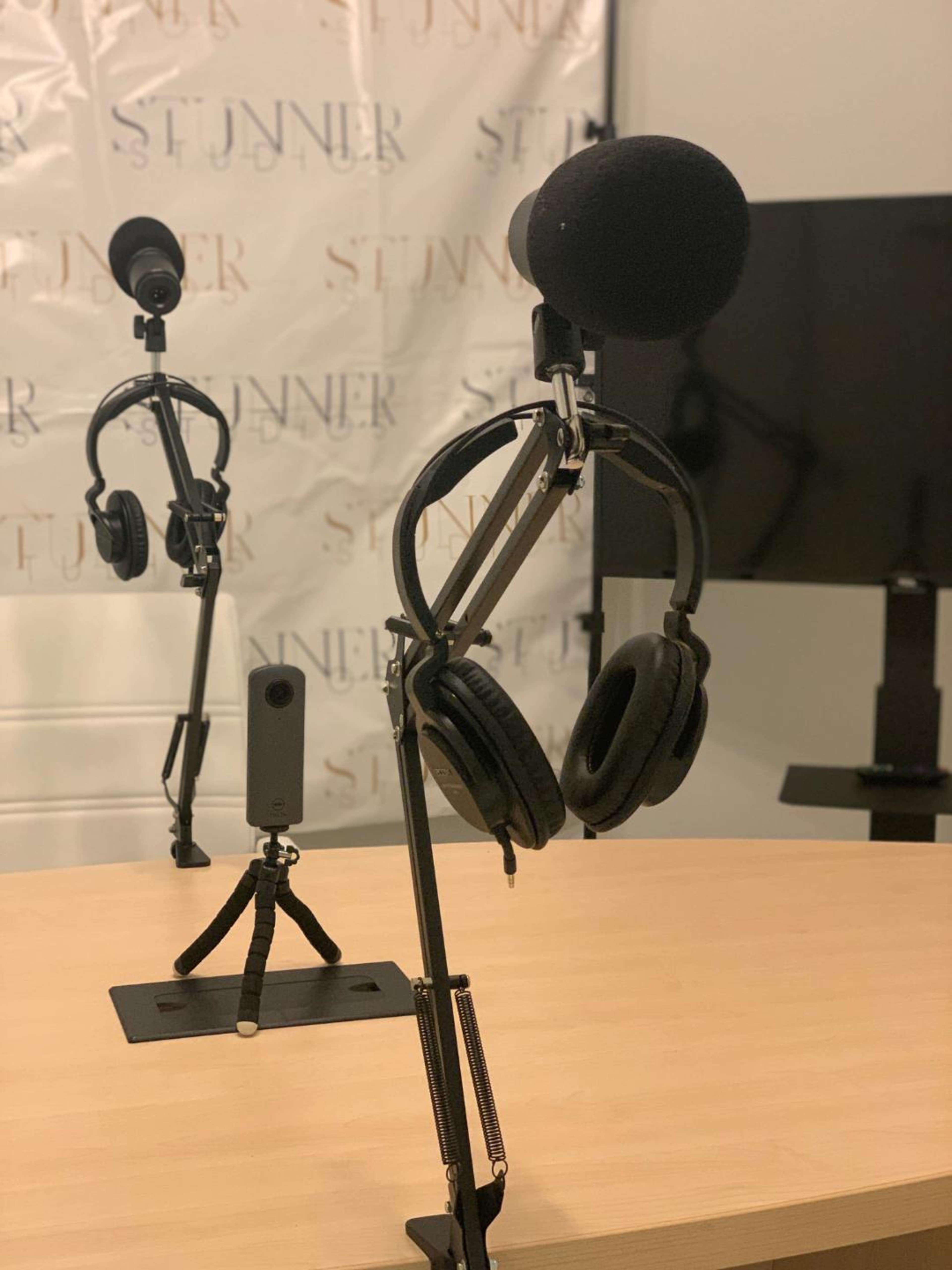 A setup with two microphones and a pair of headphones on a table, with a backdrop featuring the word "STUNNER."