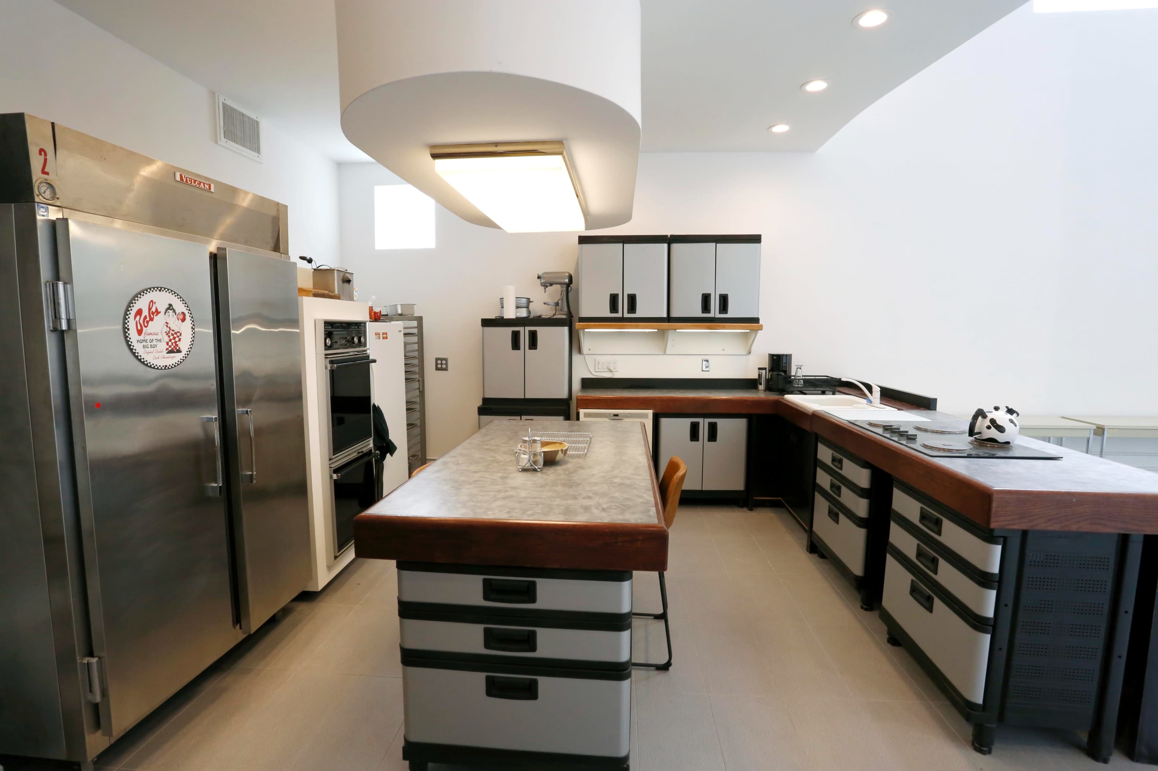 A modern kitchen featuring stainless steel appliances, a central island with a wooden top, and sleek cabinetry.